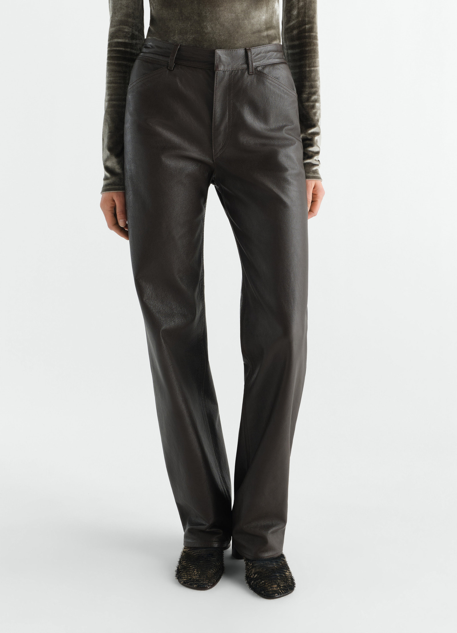 Straight black glossy leather pants lemaire worn by a model front view with textured shoes and green top