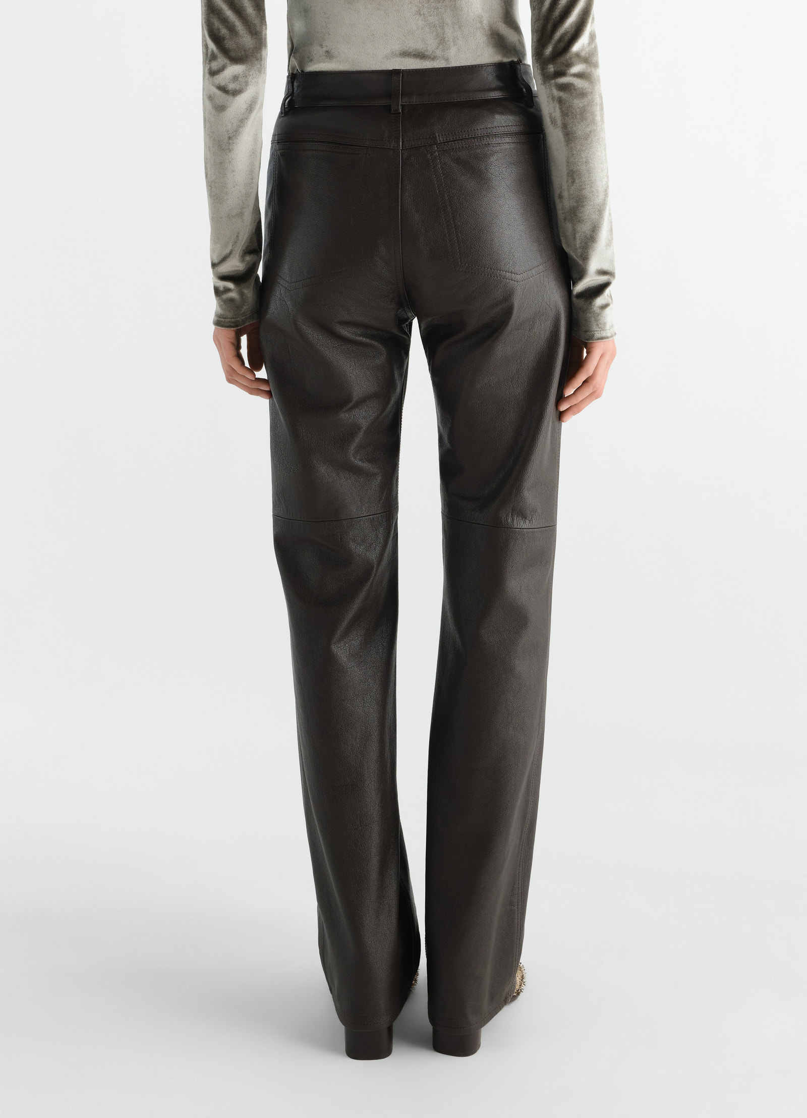 Straight black glossy leather pants by lemaire worn by a model, back view, high waist, long length.