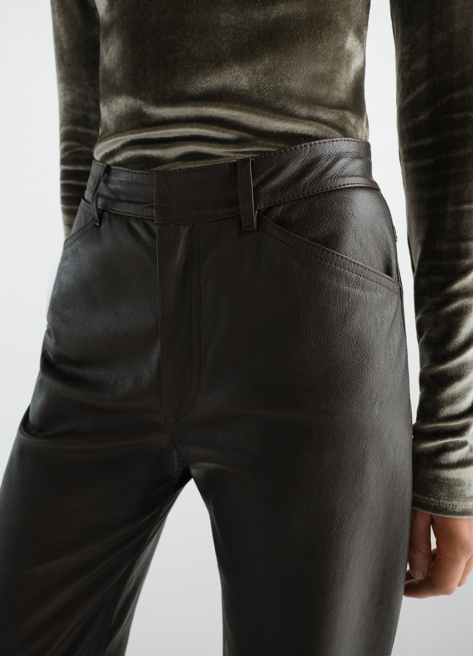 Lemaire straight glossy dark brown leather pants worn by a model close-up front detail