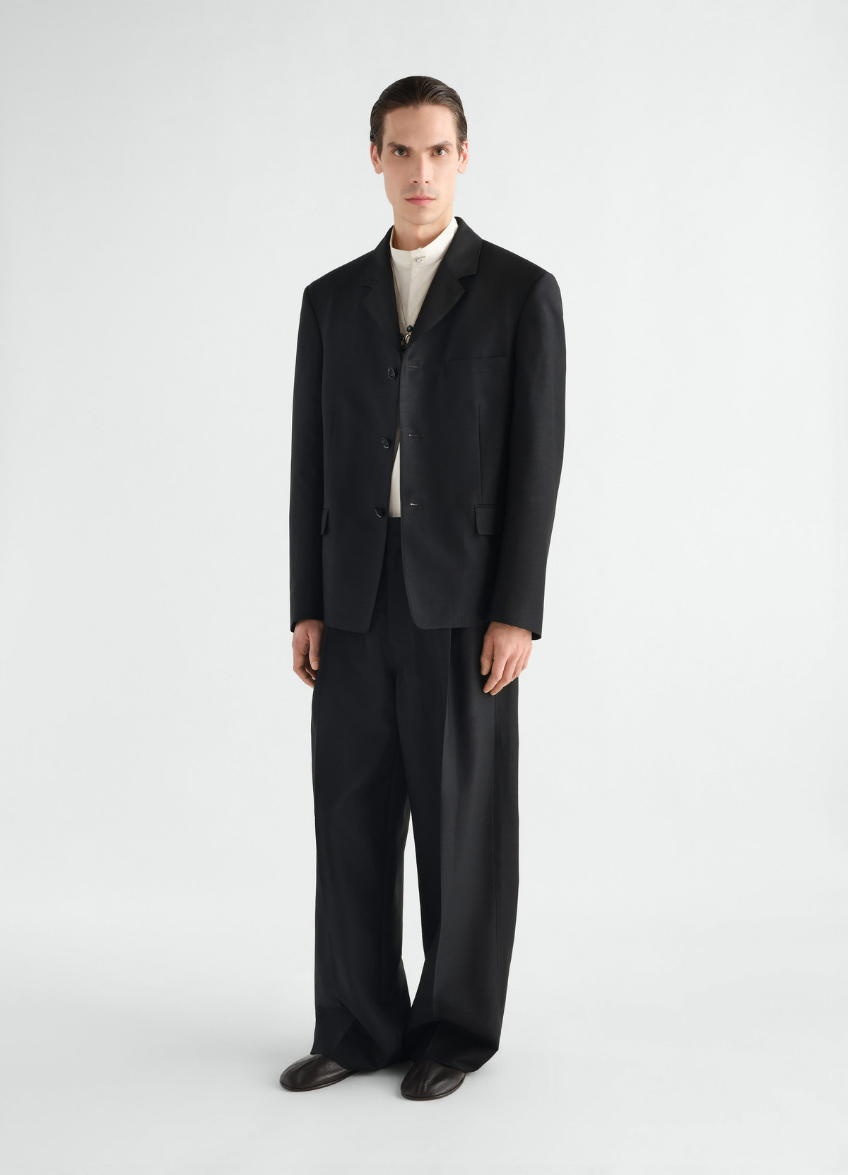 Single-pleat black wool and mohair pants lemaire worn by model front view with black blazer and white shirt