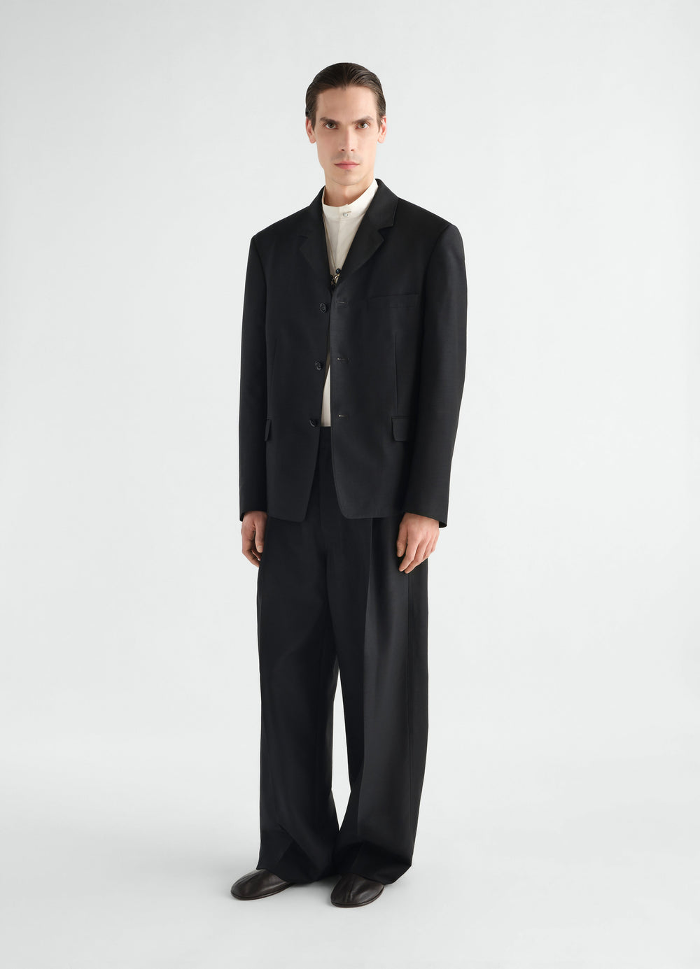 Single-pleat black wool and mohair pants LEMAIRE worn by model front view with black blazer and white shirt