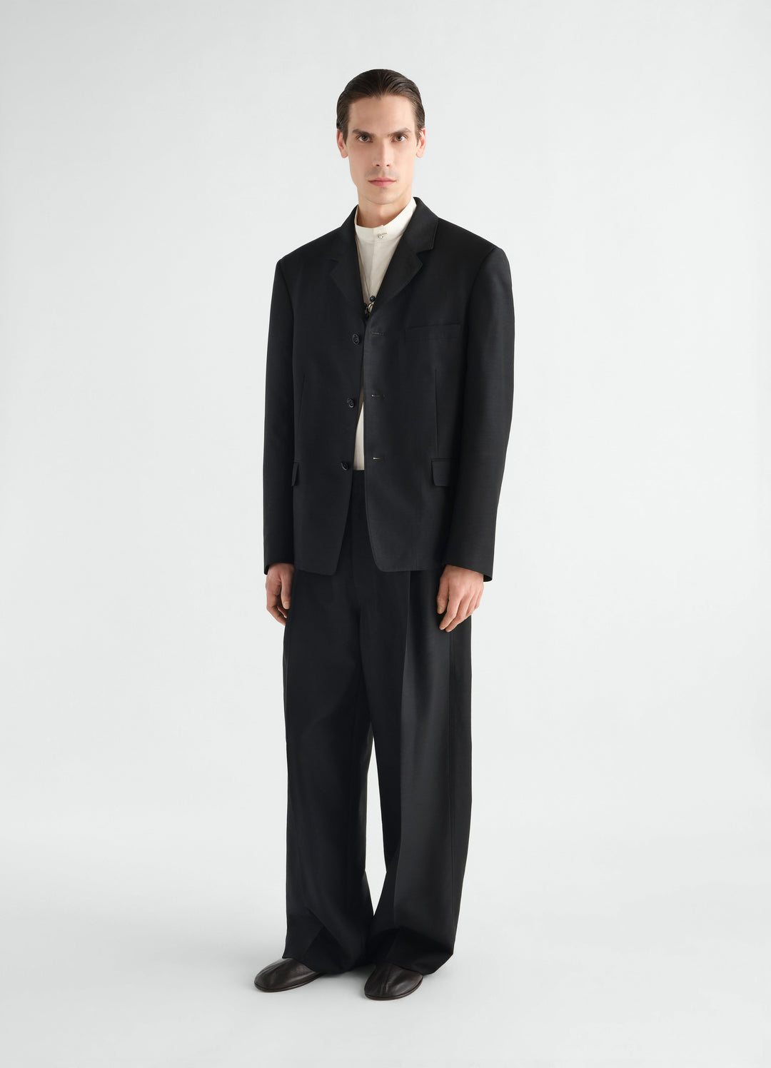 Single-pleat black wool and mohair pants LEMAIRE worn by model front view with black blazer and white shirt
