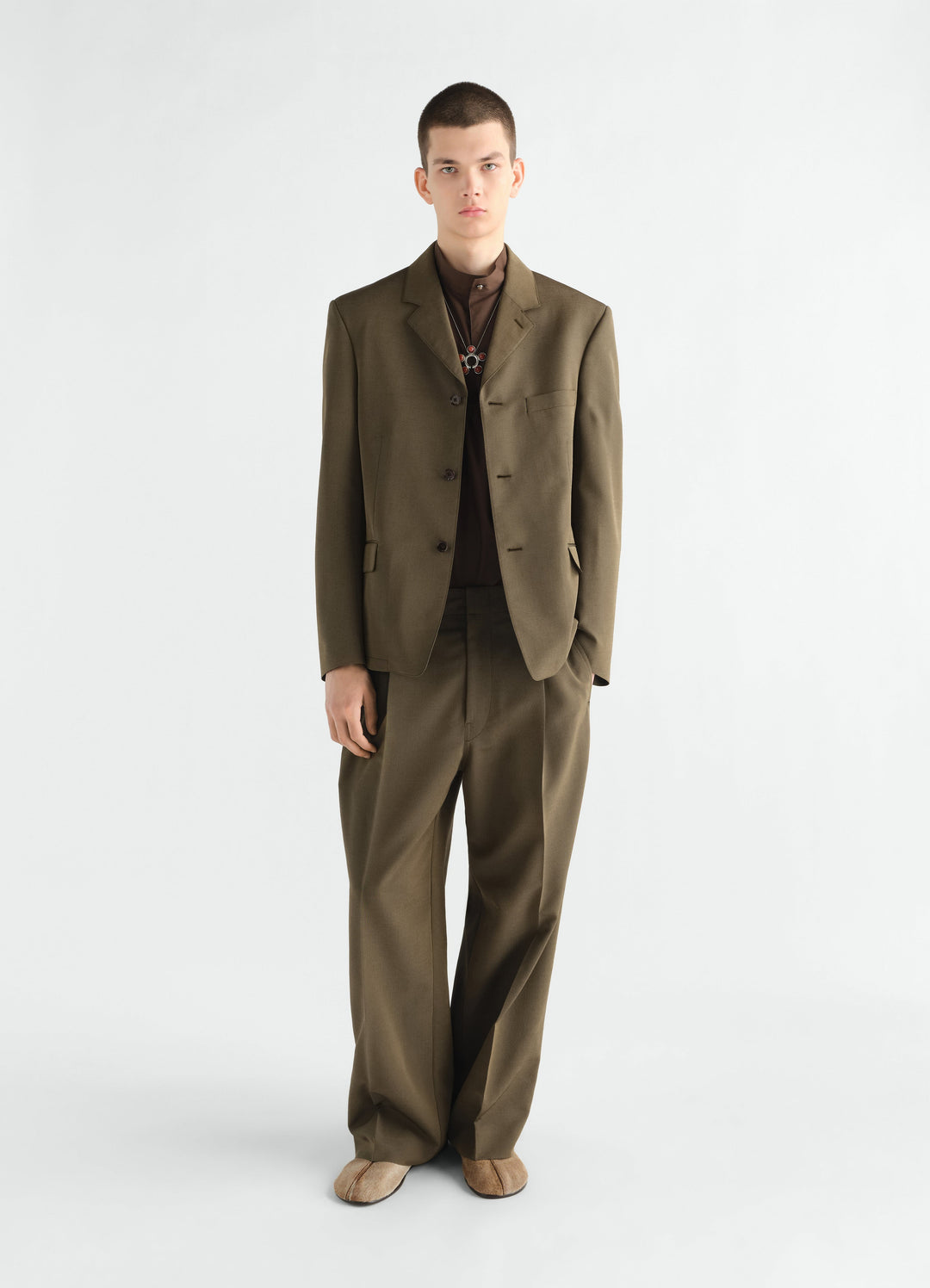 Single-pleat brown wool mohair pants by LEMAIRE worn by model front view with matching blazer on white background