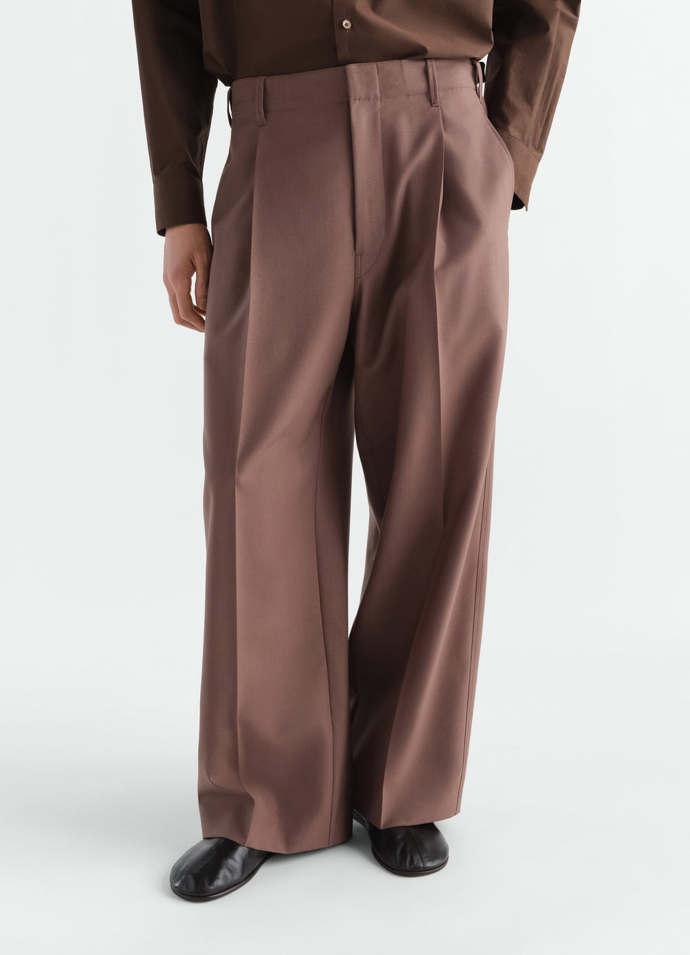 Single-pleat brown tropical wool blend tailored pants by LEMAIRE worn by a model front view