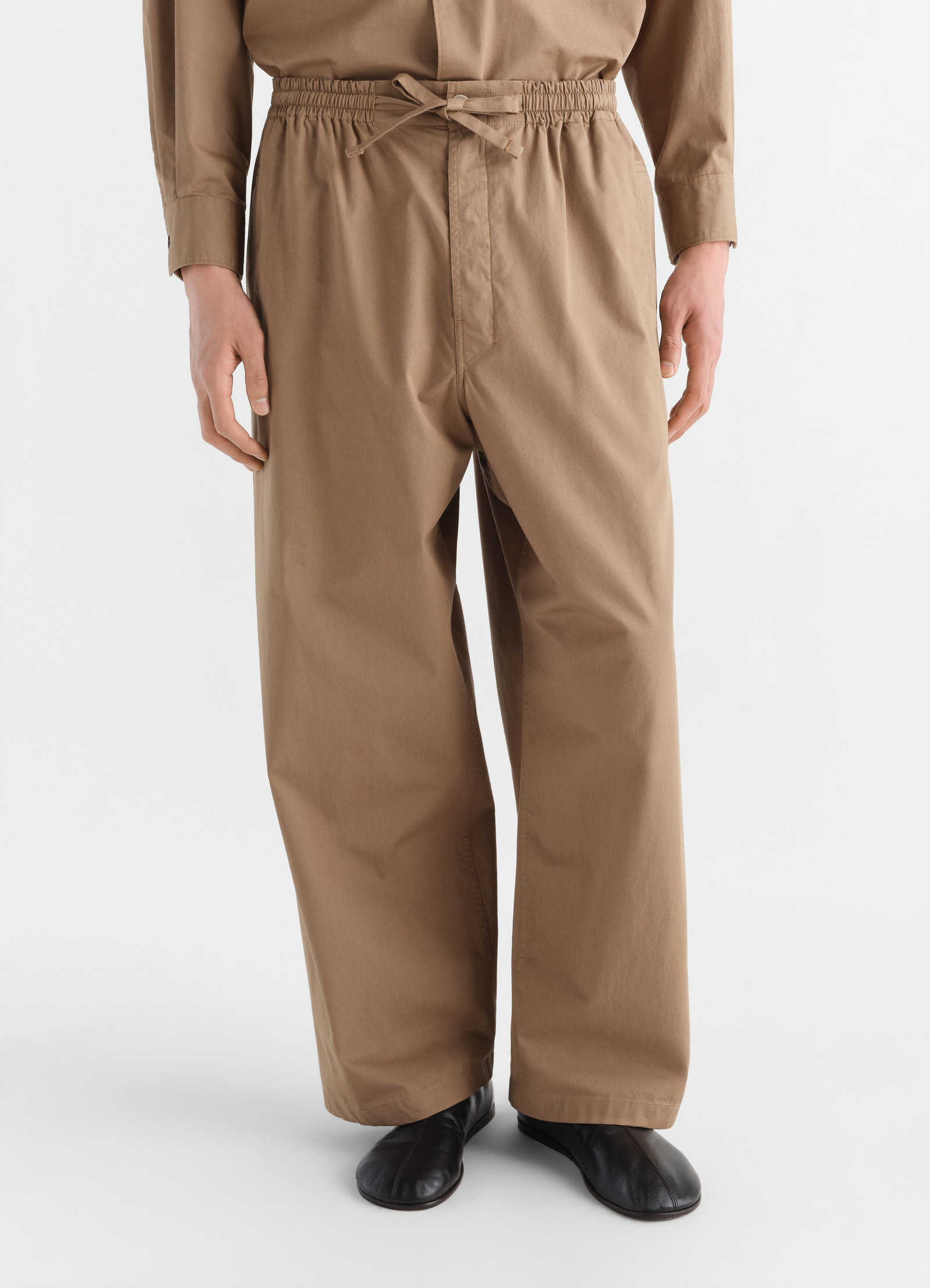 Pyjama pants lemaire in light brown cotton twill worn by model front view with drawstring waist and wide leg