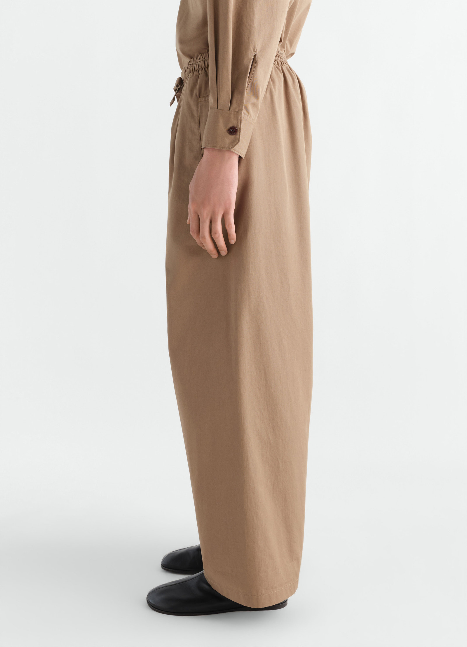 Lemaire light brown cotton twill pyjama pants worn by a model side view with black shoes