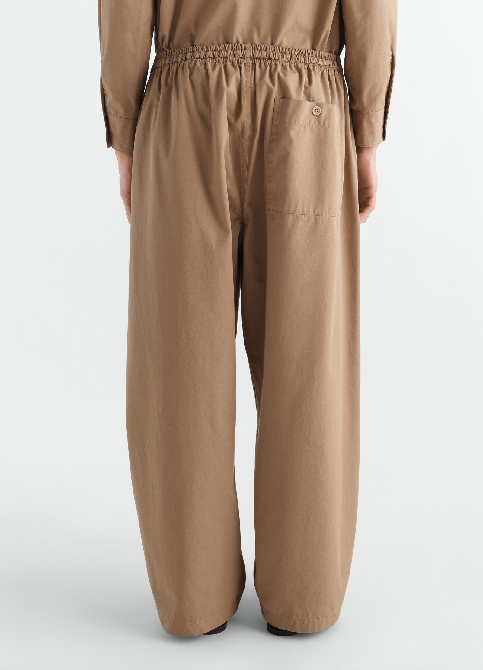 Pyjama pants in light brown cotton twill with elastic waist and back pocket by lemaire worn by a model back view