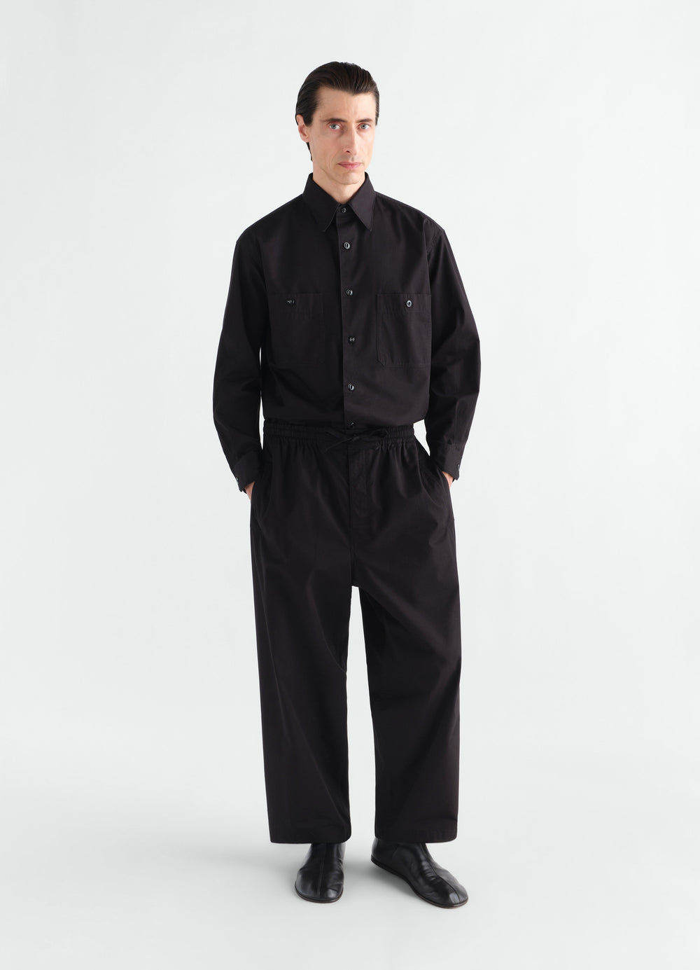Pyjama pants in black light cotton twill worn by a model front view LEMAIRE