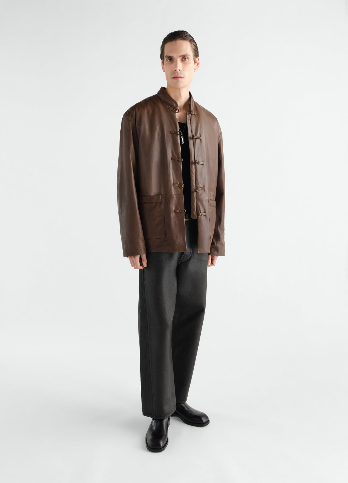 Straight black coated denim five-pocket pants LEMAIRE worn by model front with black leather boots