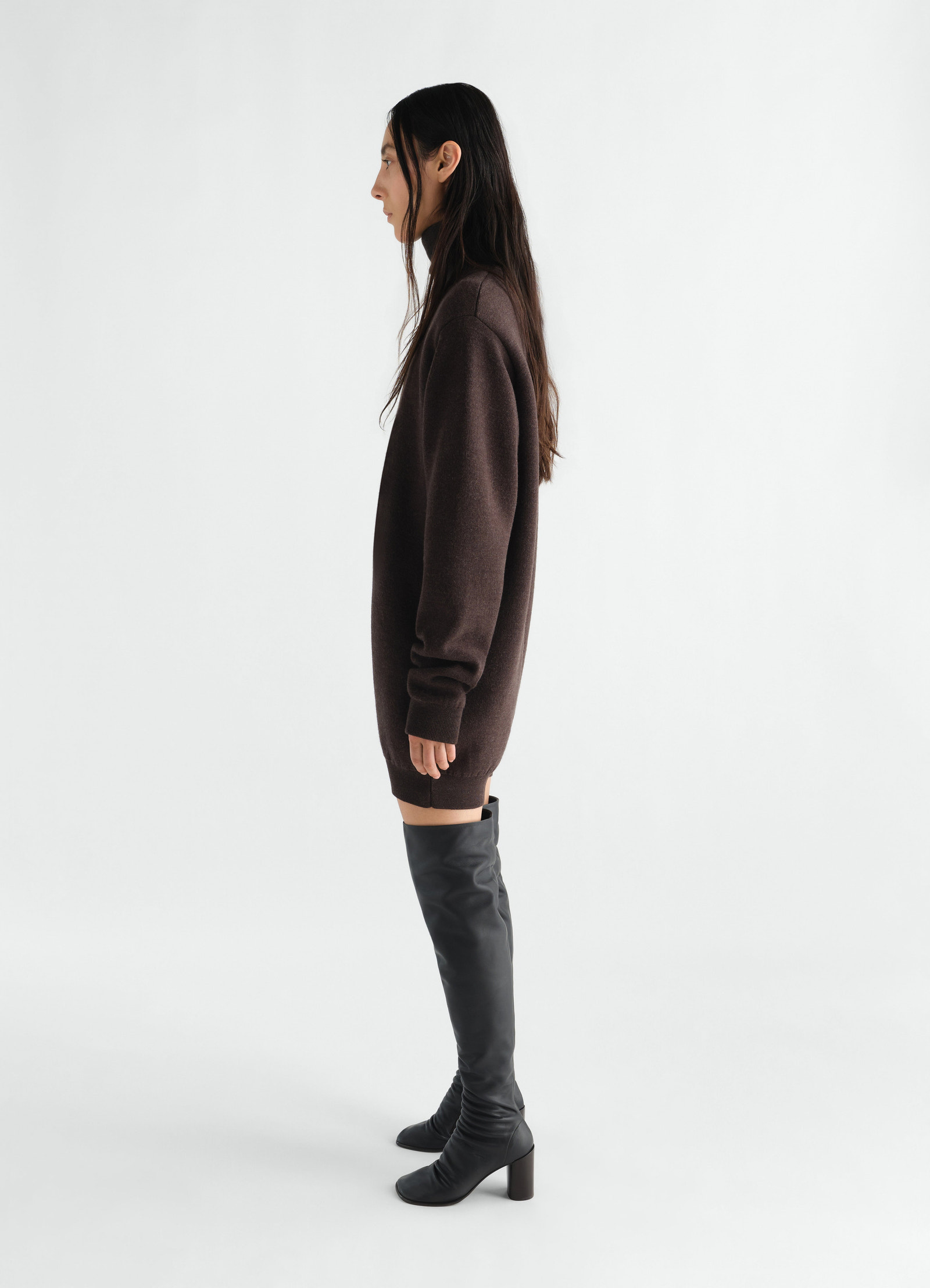 Relaxed brown felted merino wool jumpsuit by lemaire worn by model side view with black leather knee-high boots
