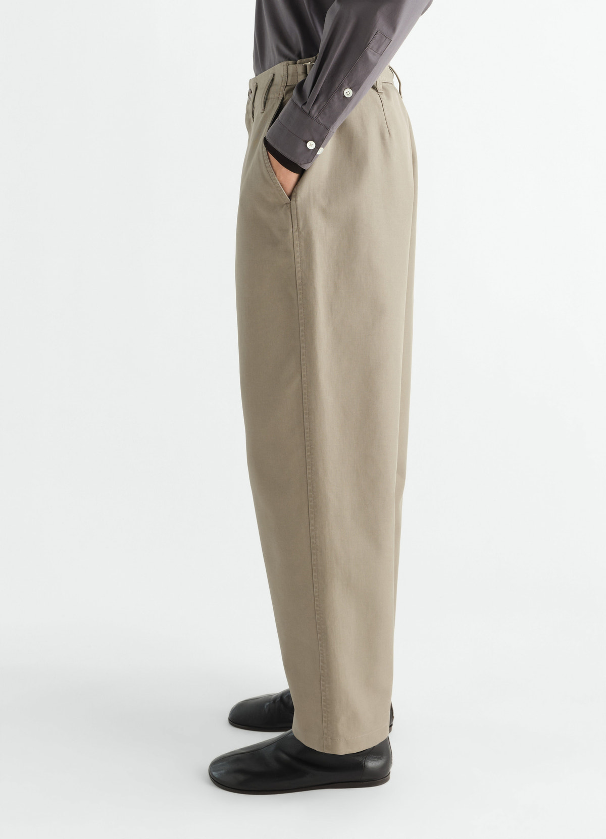 Tapered beige heavy cotton twill pants by lemaire worn by model side view with black shoes and grey shirt