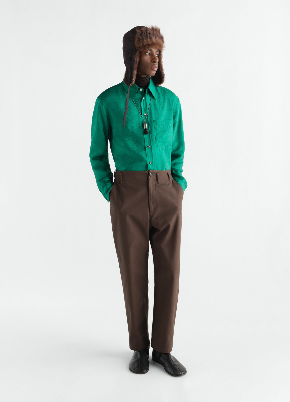 Tapered brown heavy cotton twill pants lemaire worn by model with green shirt and fur hat front view