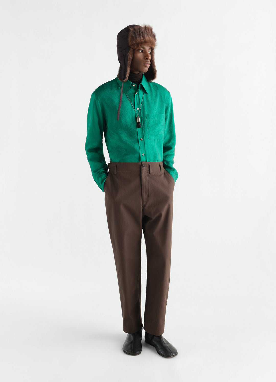 Tapered brown heavy cotton twill pants LEMAIRE worn by model with green shirt and fur hat front view
