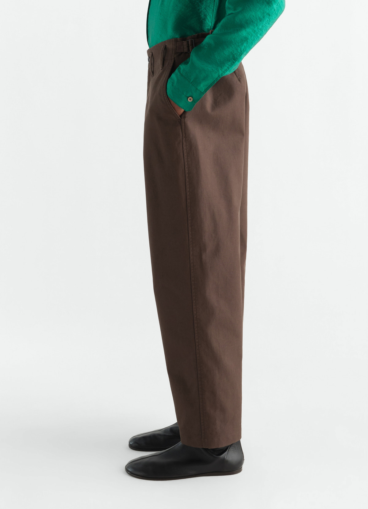 Tapered brown heavy cotton twill pants lemaire worn by model side view with green shirt and black shoes