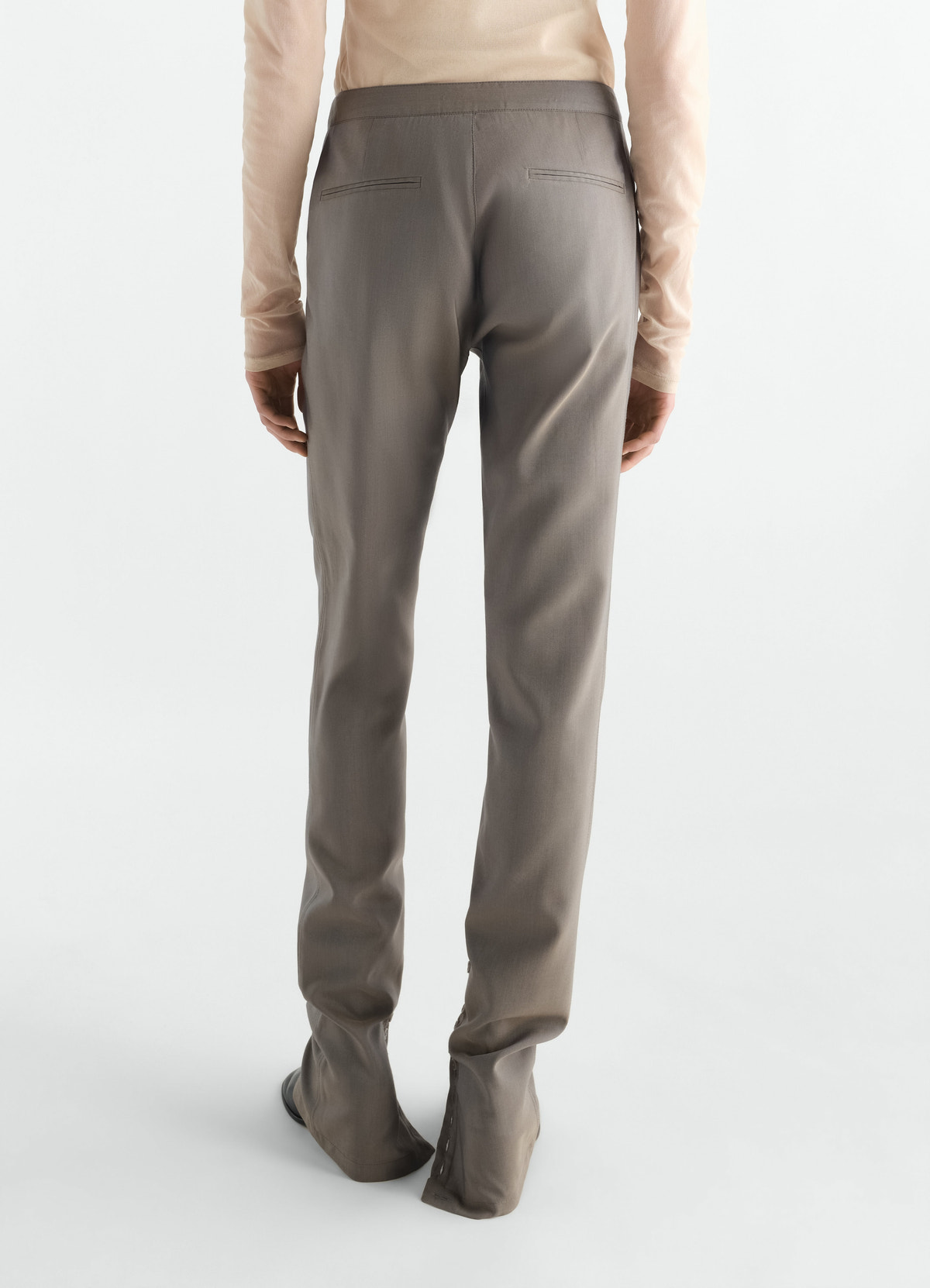 Pantalon tailleur en toile de laine et mohair avec guêtres intégrées, coloris gris, porté par un mannequin, vue de dos
