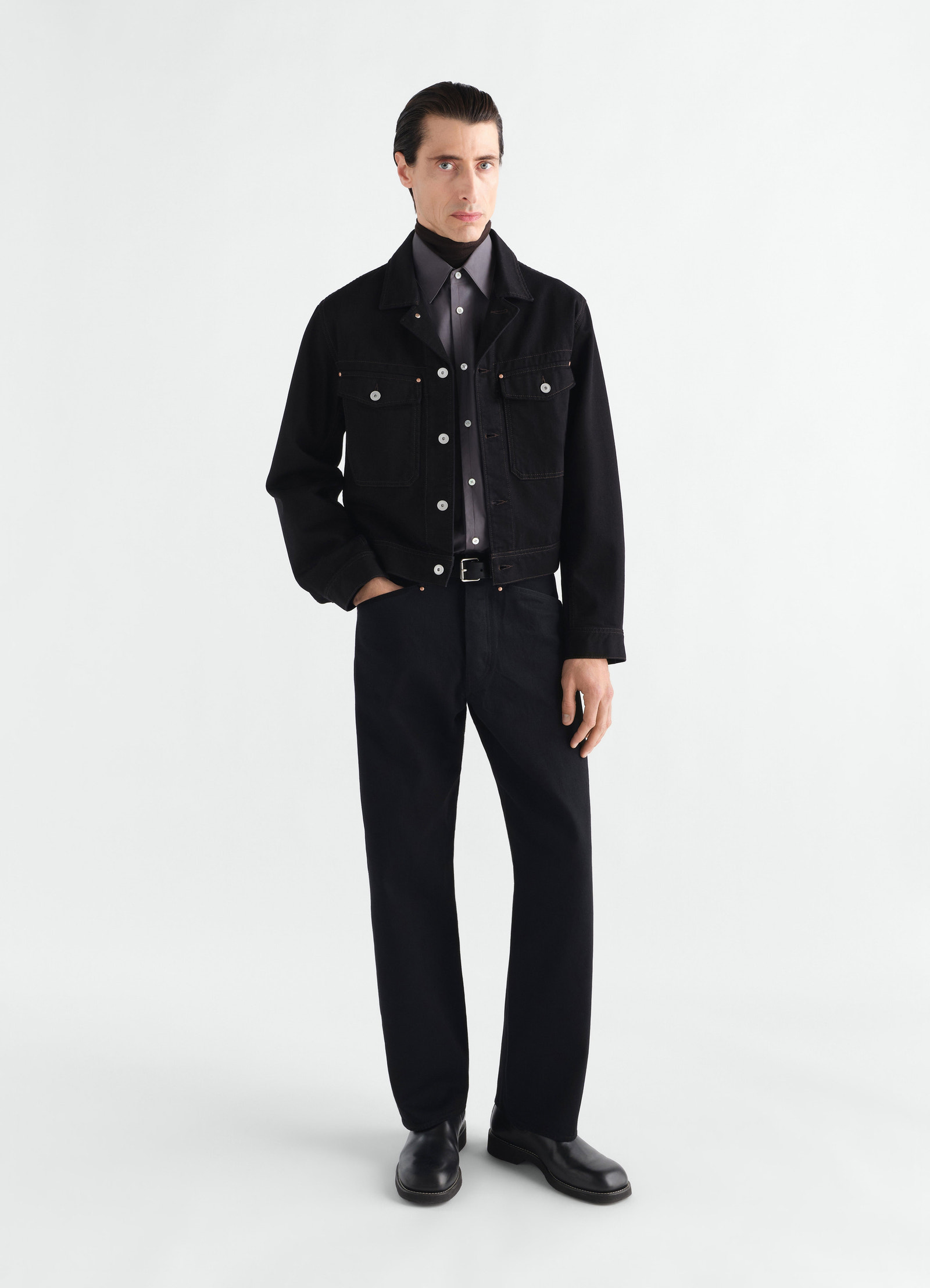 Straight five-pocket black selvedge denim pants lemaire worn by model front view with black jacket and shoes