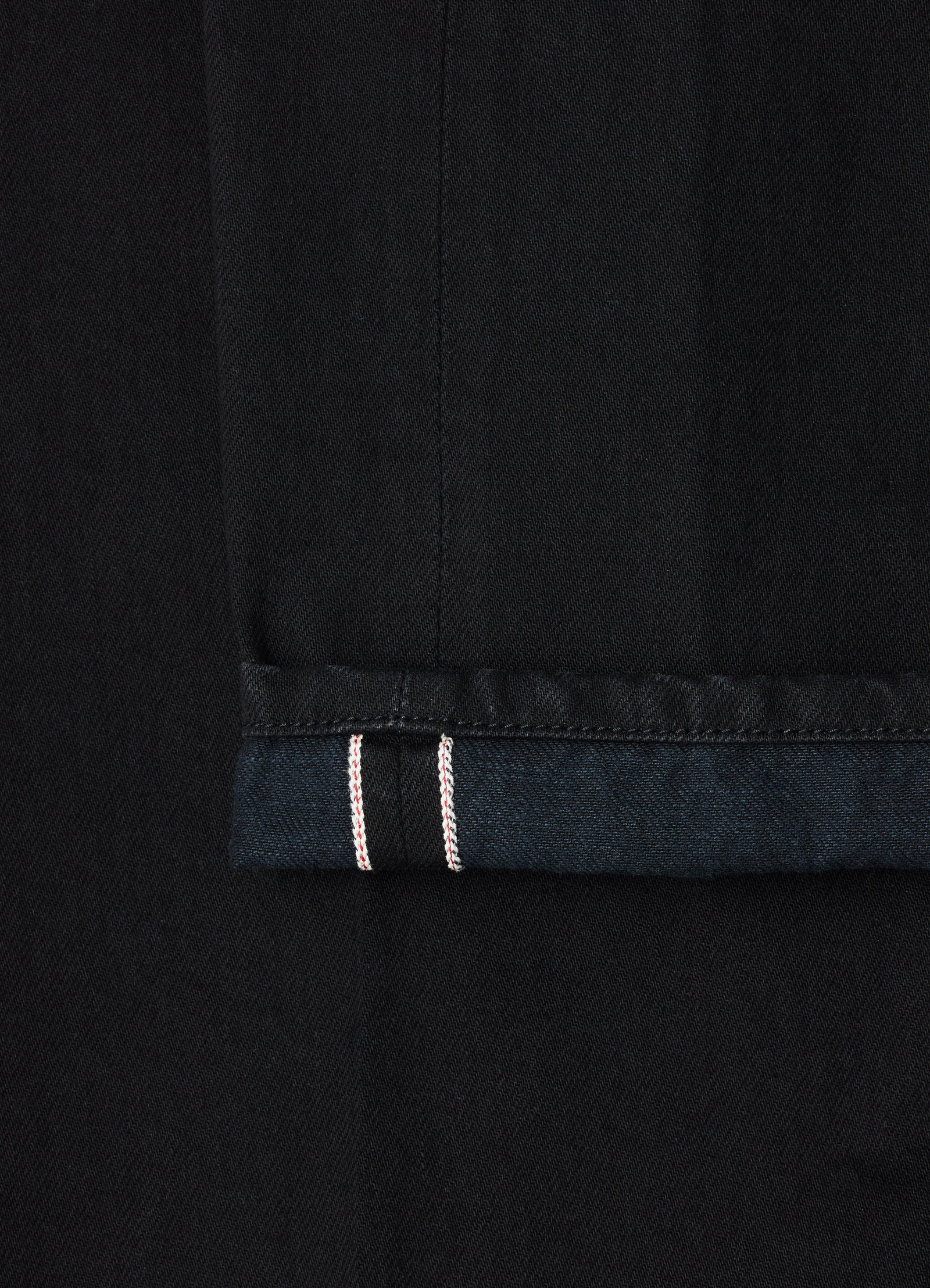 Straight five-pocket pants black selvedge denim lemaire close-up of hem detail with red stitching