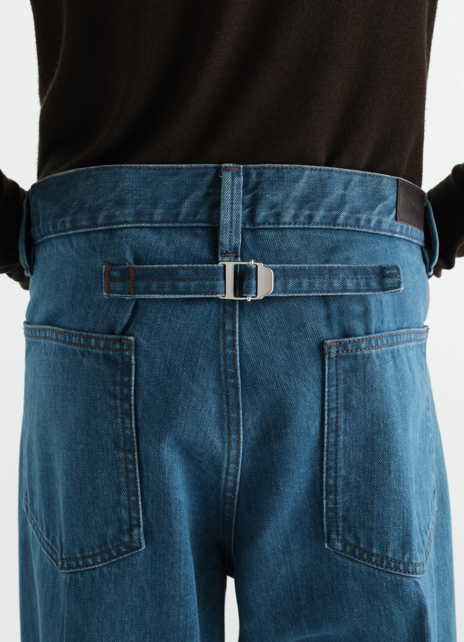 Straight indigo selvedge denim pants with adjustable back strap and pockets worn by model lemaire