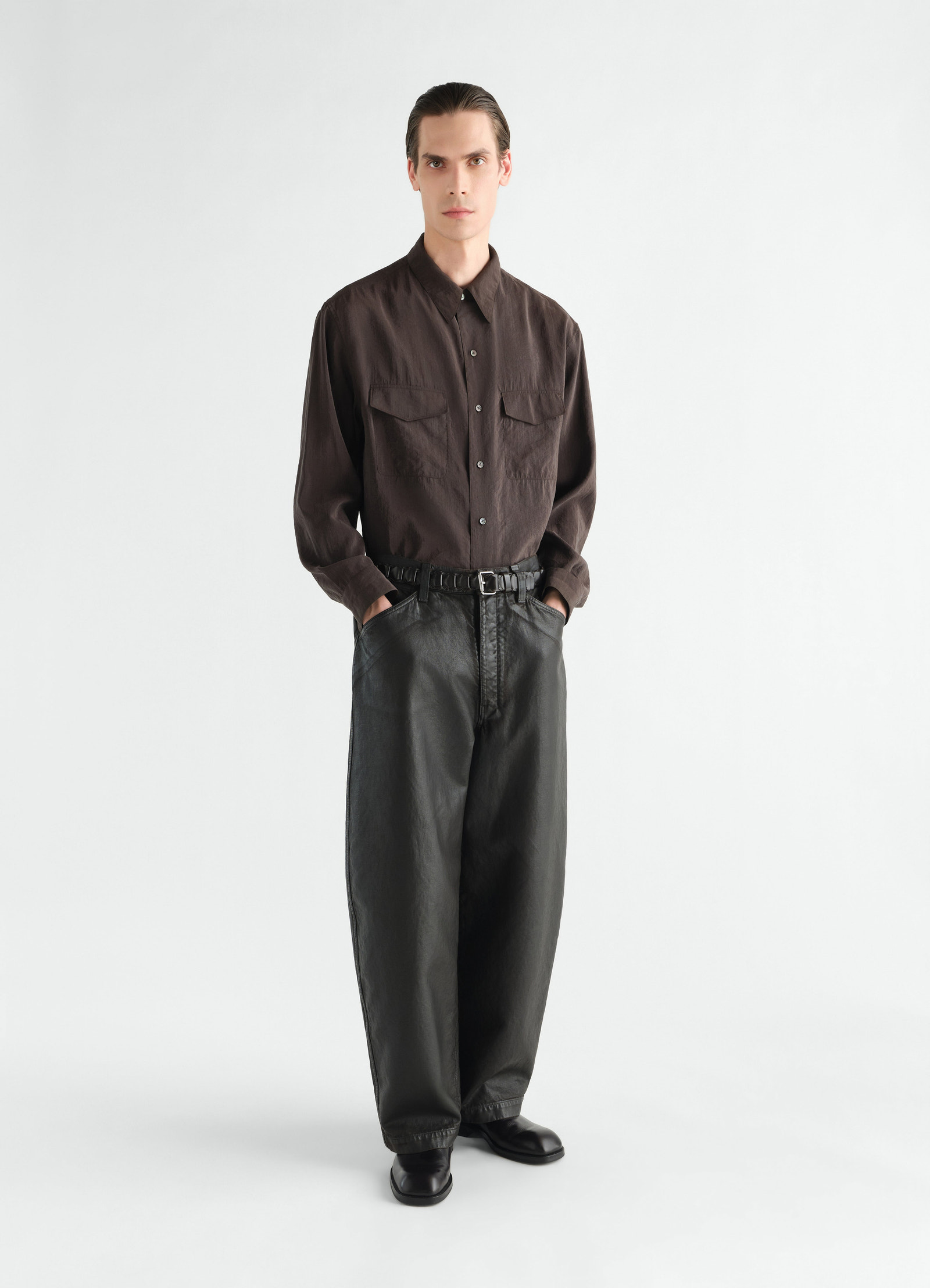 Oversized black coated denim pants lemaire worn by a model front view with belt and black boots