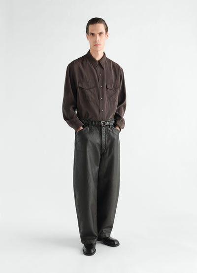Oversized black coated denim pants LEMAIRE worn by a model front view with belt and black boots