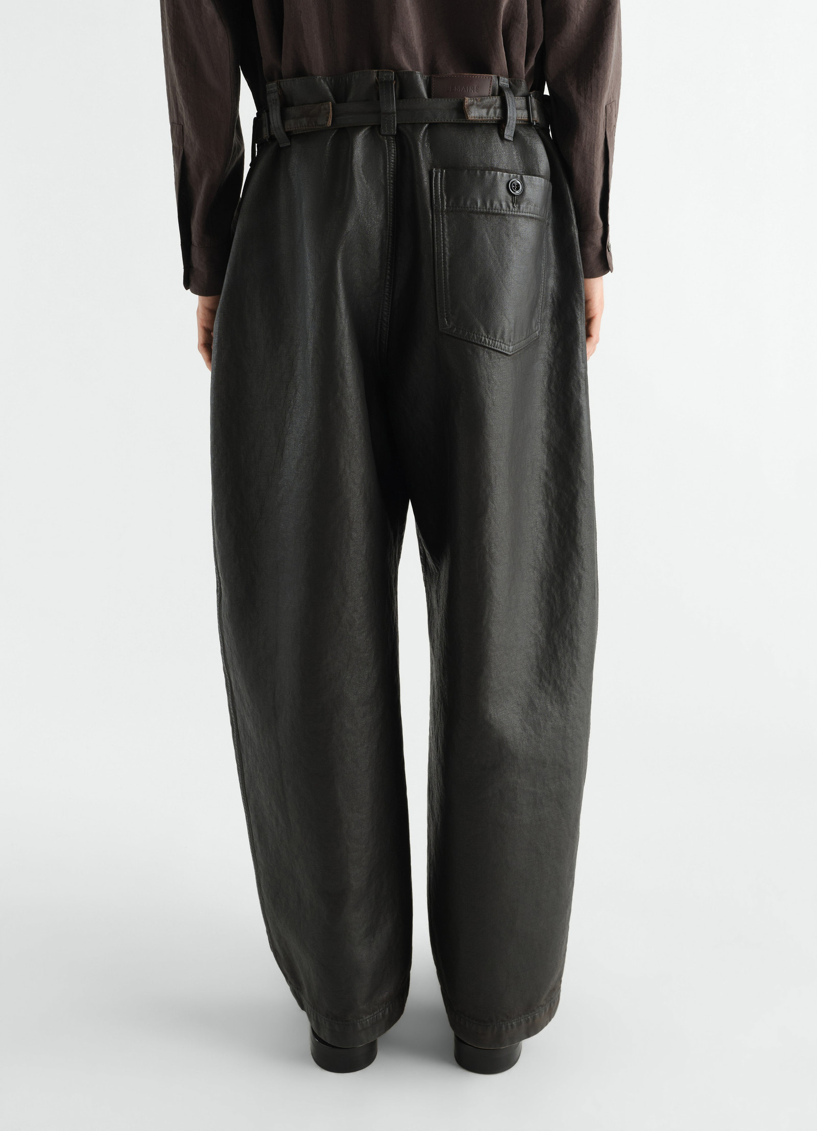 Oversized black coated denim workwear pants by lemaire, rear view worn by model with belt details