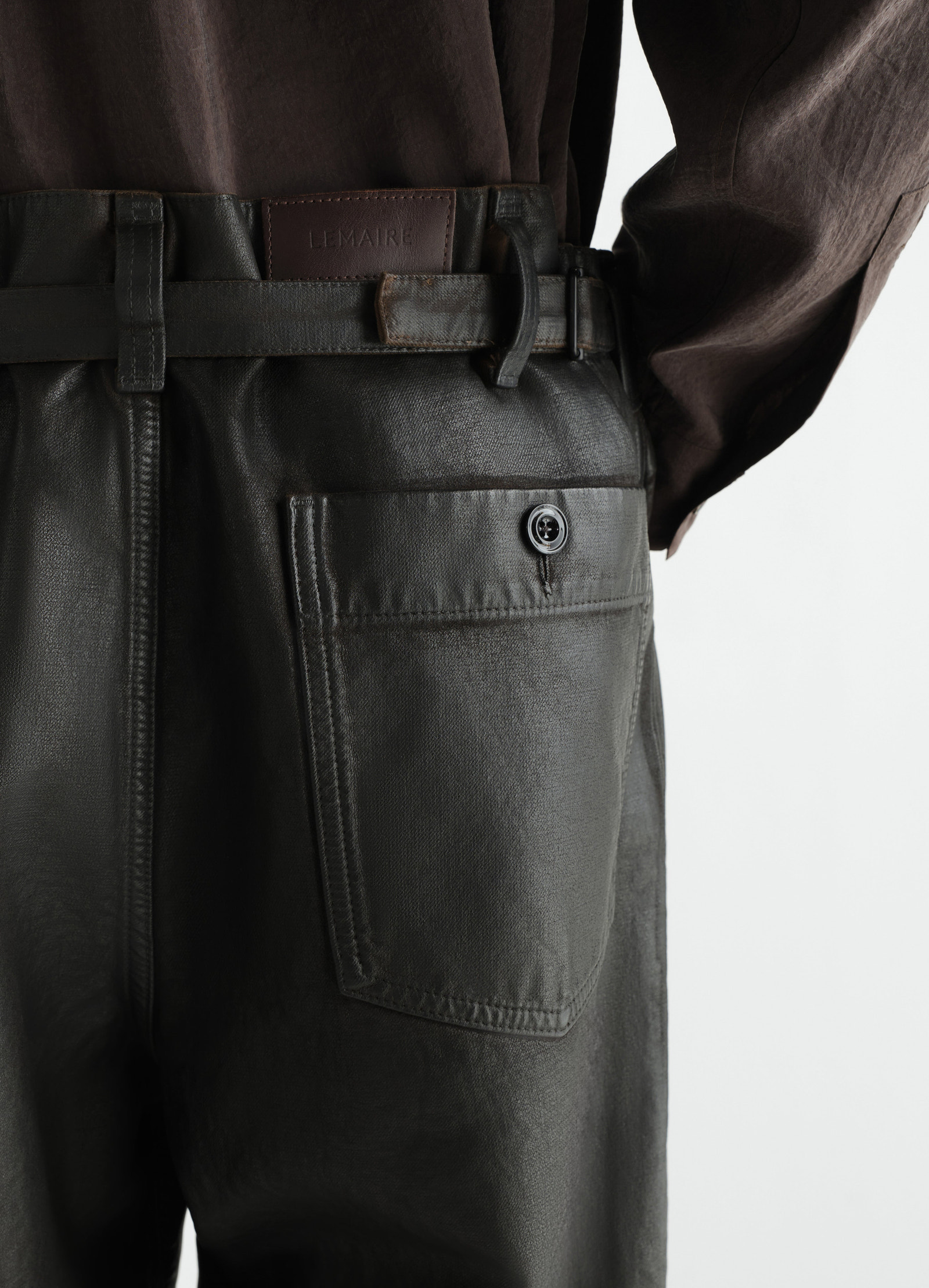 Oversized black coated denim pants lemaire back pocket detail worn by a model with brown top