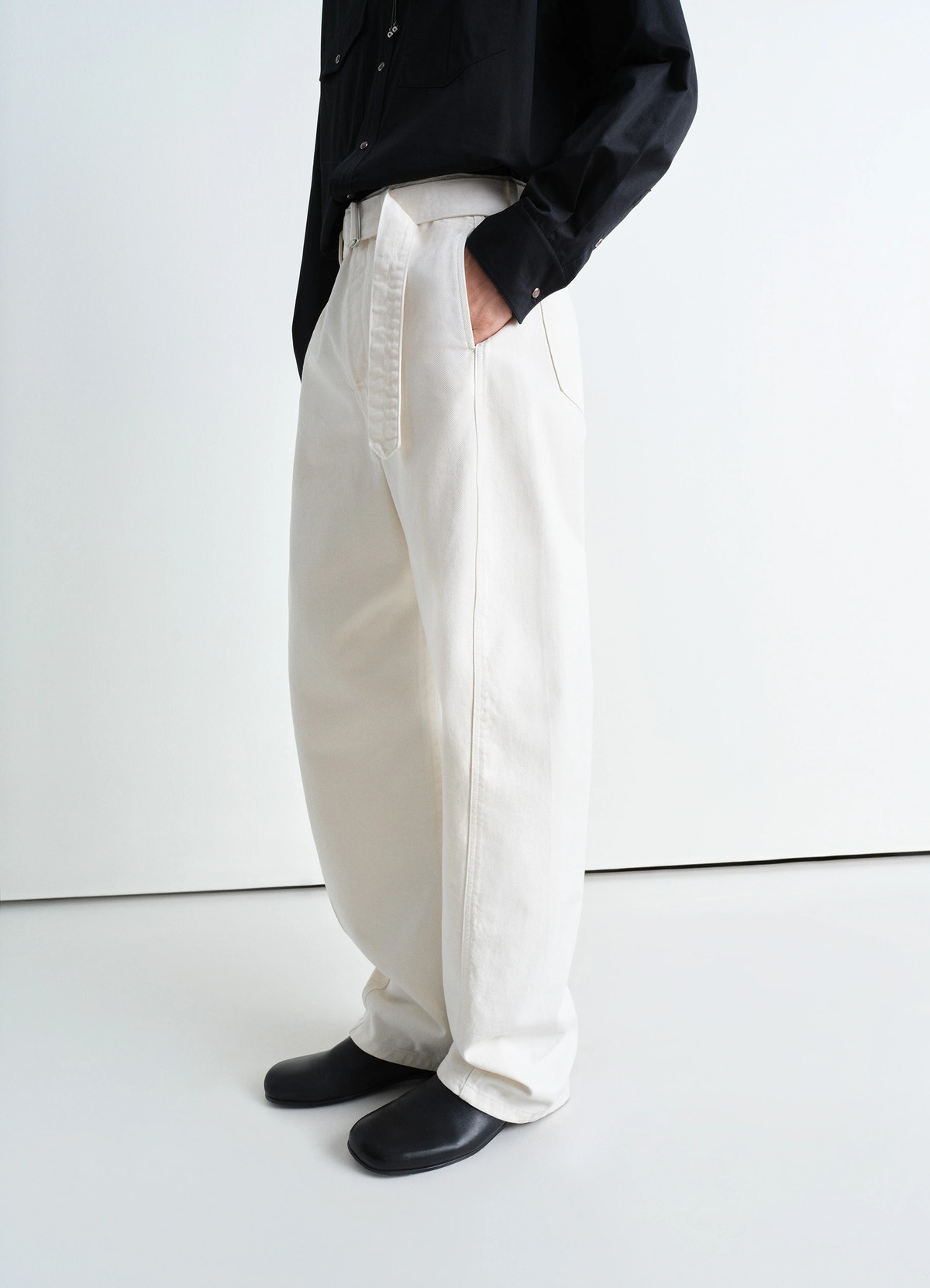 Lemaire twisted belted pants in garment dyed snow heavy denim, model shot, three-quarter side view wide leg relaxed fit