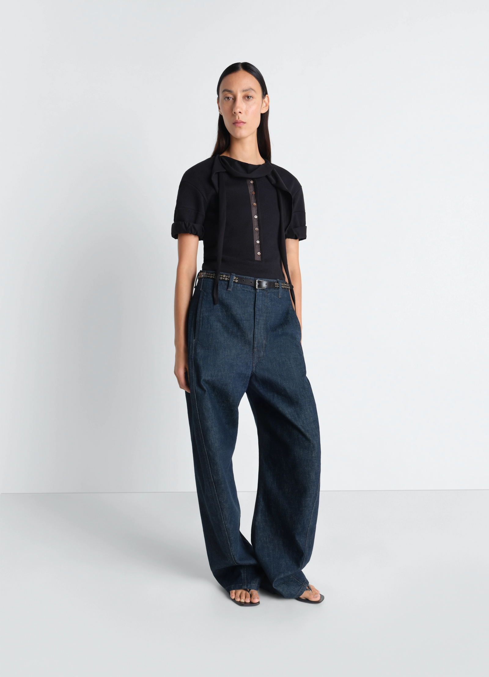 Twisted belted pants in denim in deep indigo garment-dyed denim, model shot, three-quarter view belted waist, relaxed fit