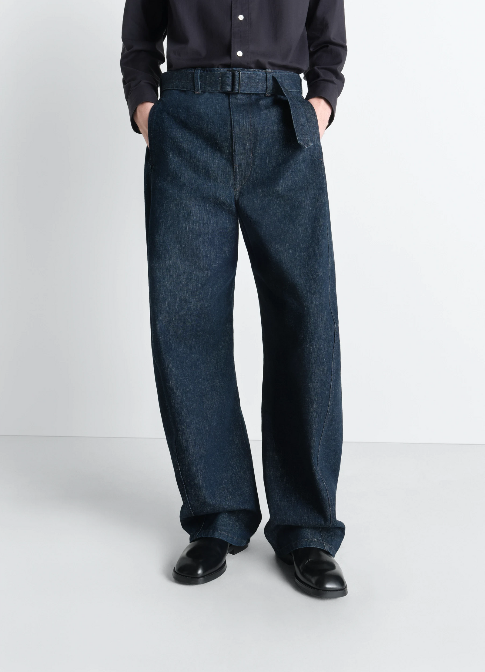 Twisted belted pants in denim in deep indigo garment-dyed denim, model shot, side view twisted seams relaxed fit