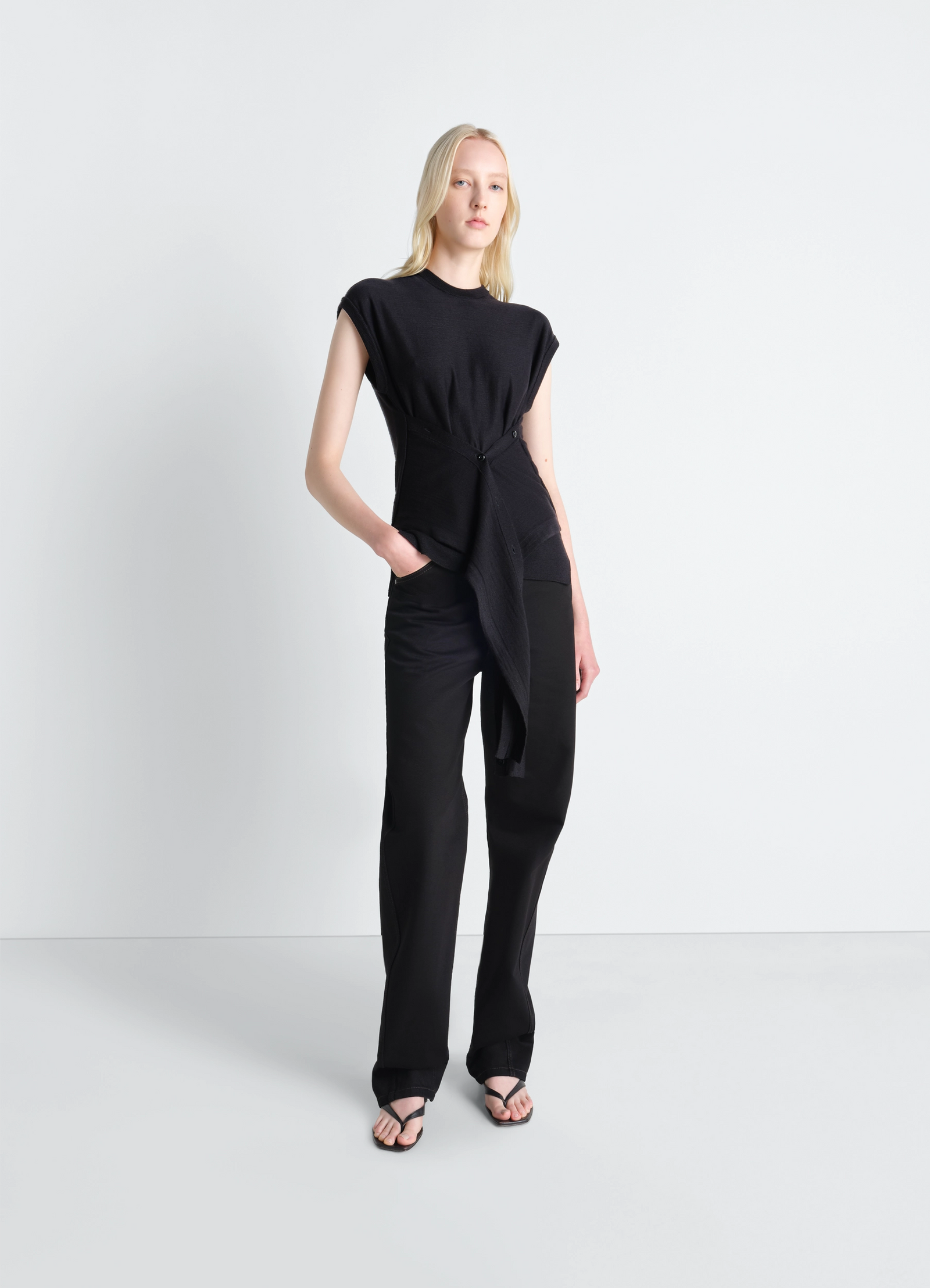 Sleeveless buttoned top in black merino blend, model shot, three-quarter view draped waistline