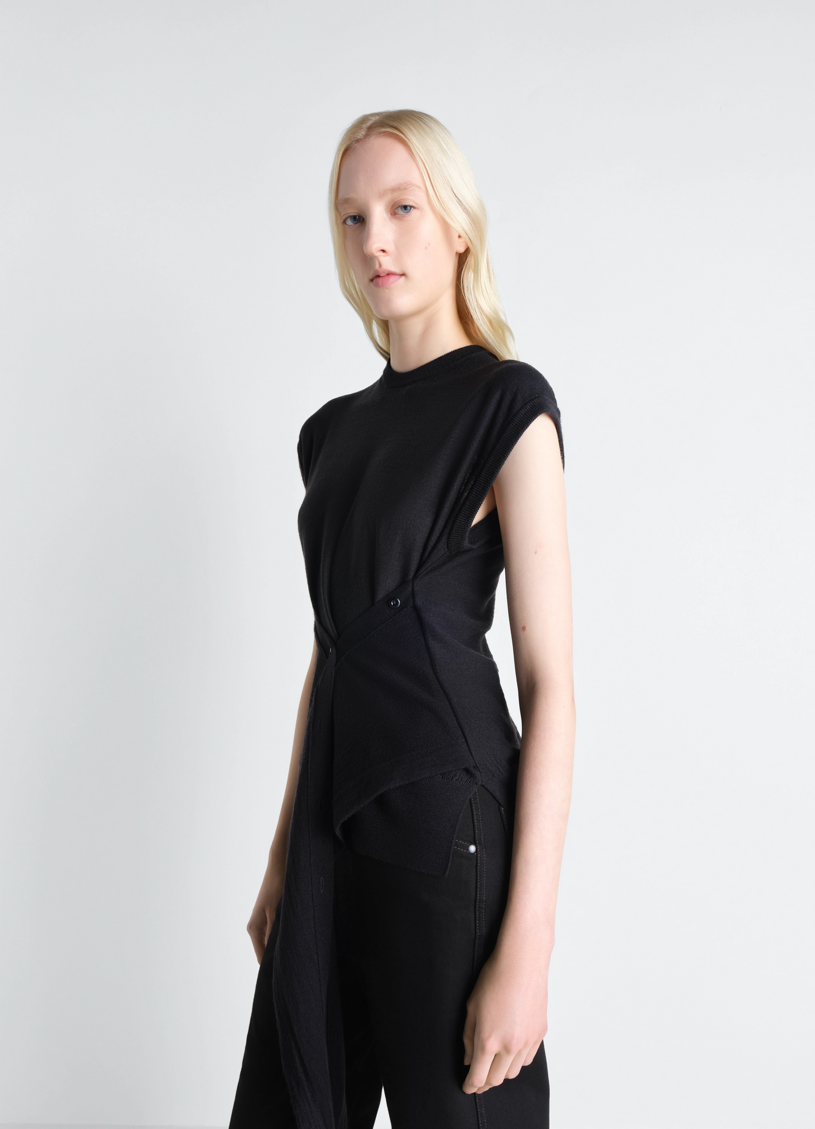 Sleeveless buttoned top in black merino blend, model shot, side view asymmetric hem