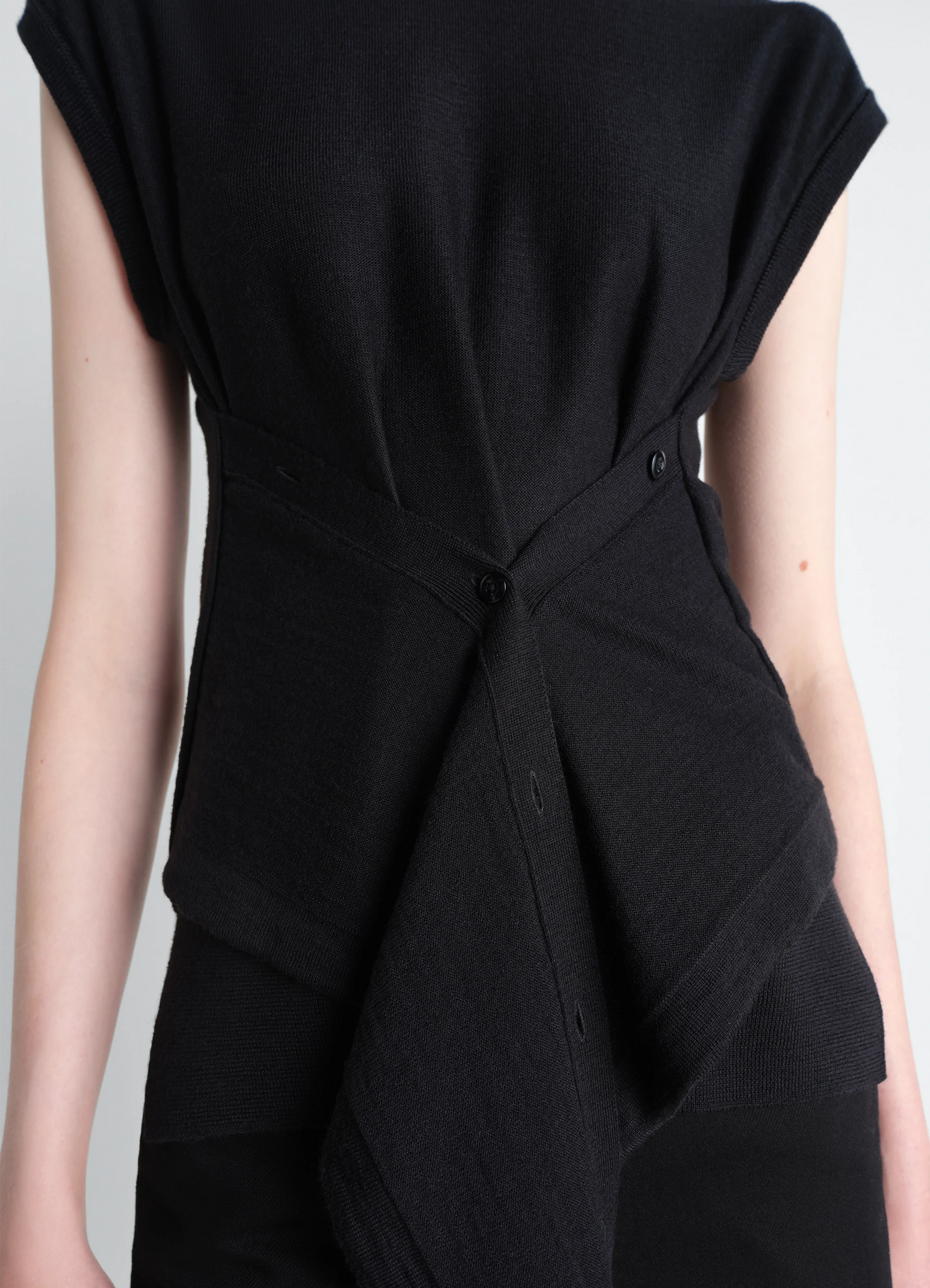 Sleeveless buttoned top in black merino blend, model shot, close-up view crossed button design