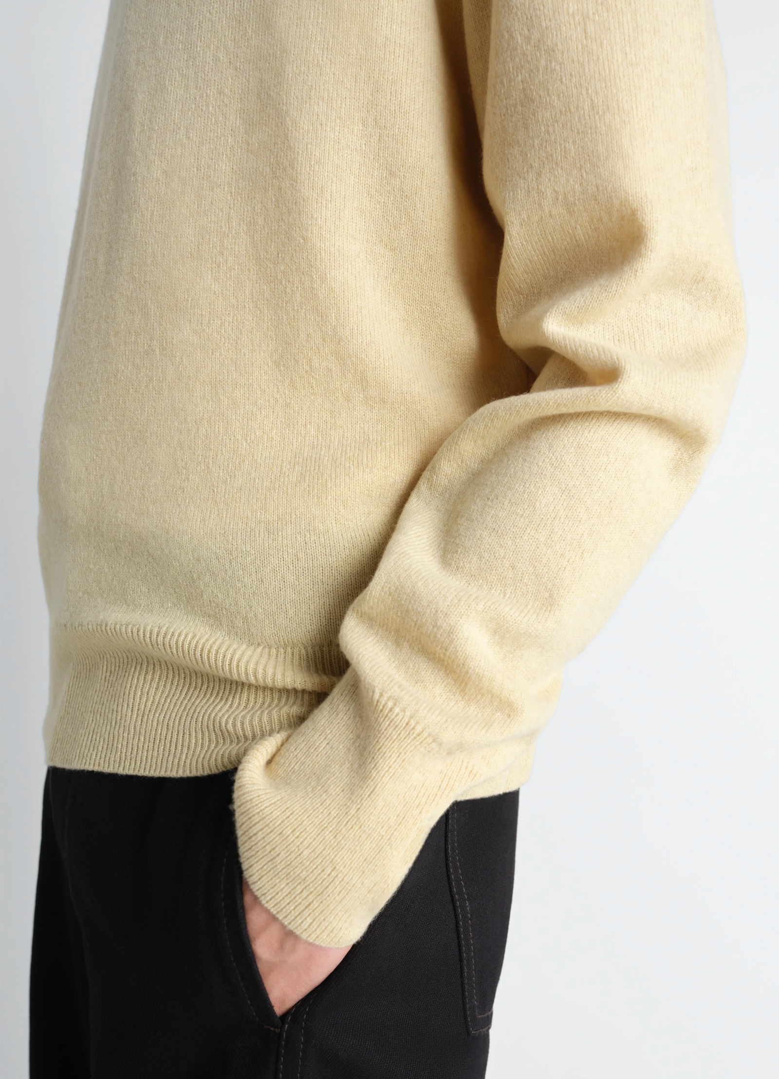 Lemaire crew neck sweater in cashmere wool, model shot, close-up side detail sleeve drape over dark pants