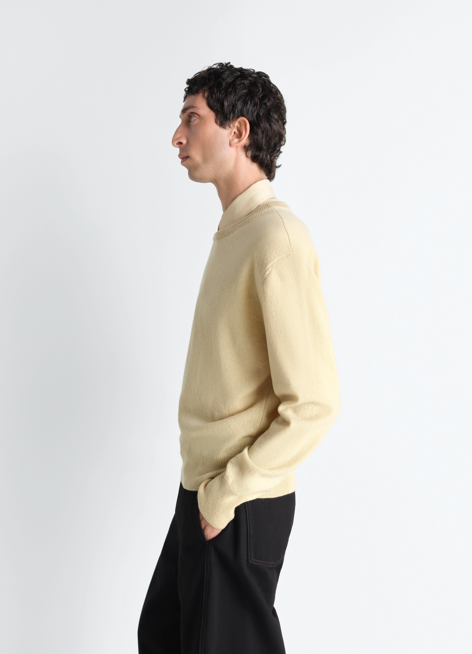 Lemaire crew neck sweater in cashmere wool, model shot, side profile view hands in pocket