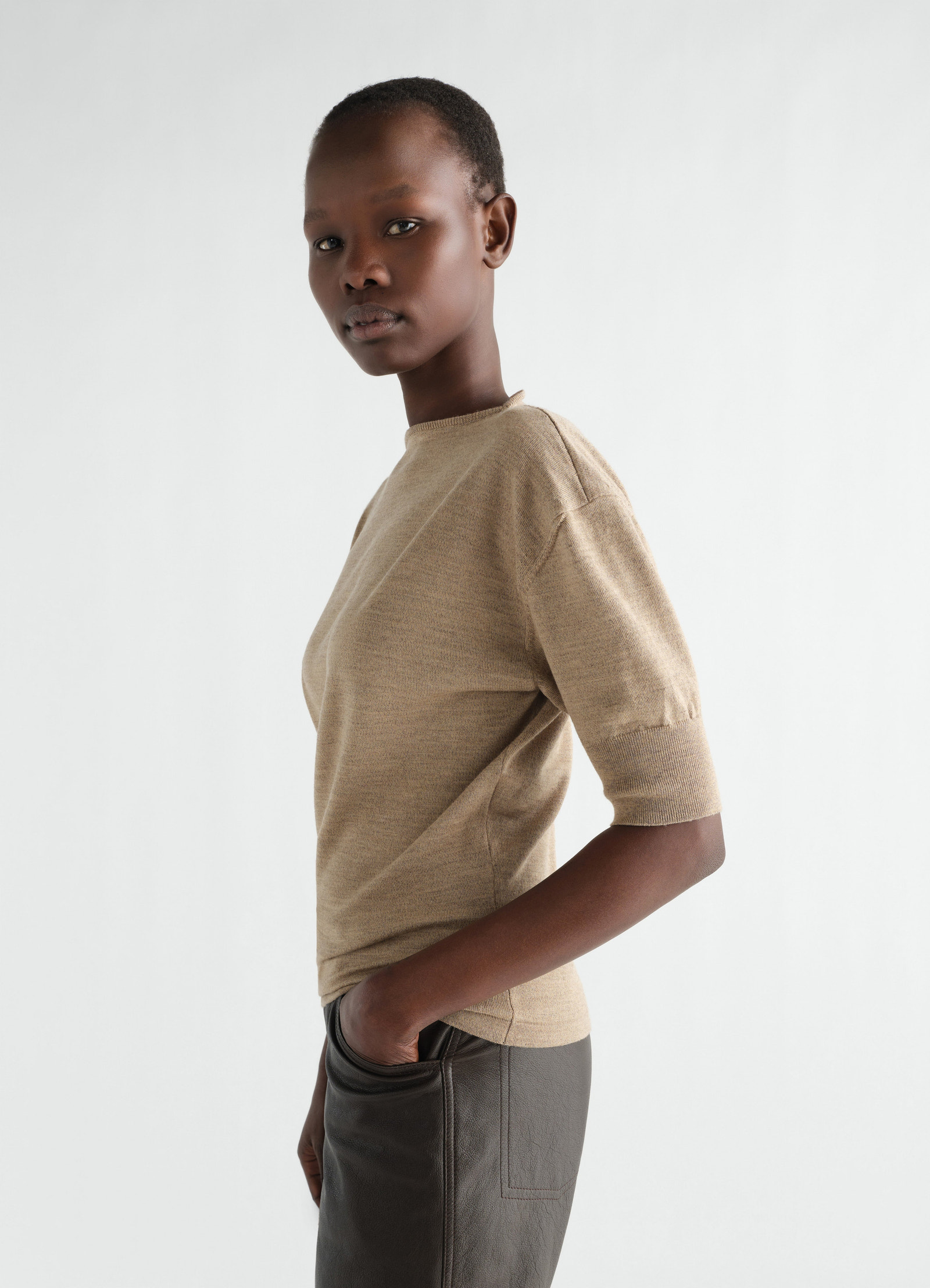 Beige fine merino wool short-sleeve sweater by lemaire worn by a model side view on plain background