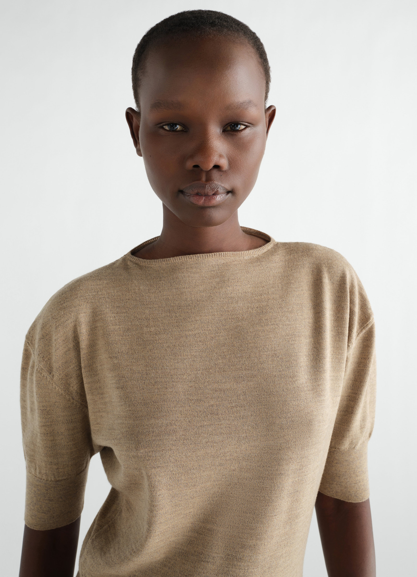 Short-sleeve beige fine merino wool sweater worn by a model front view lemaire