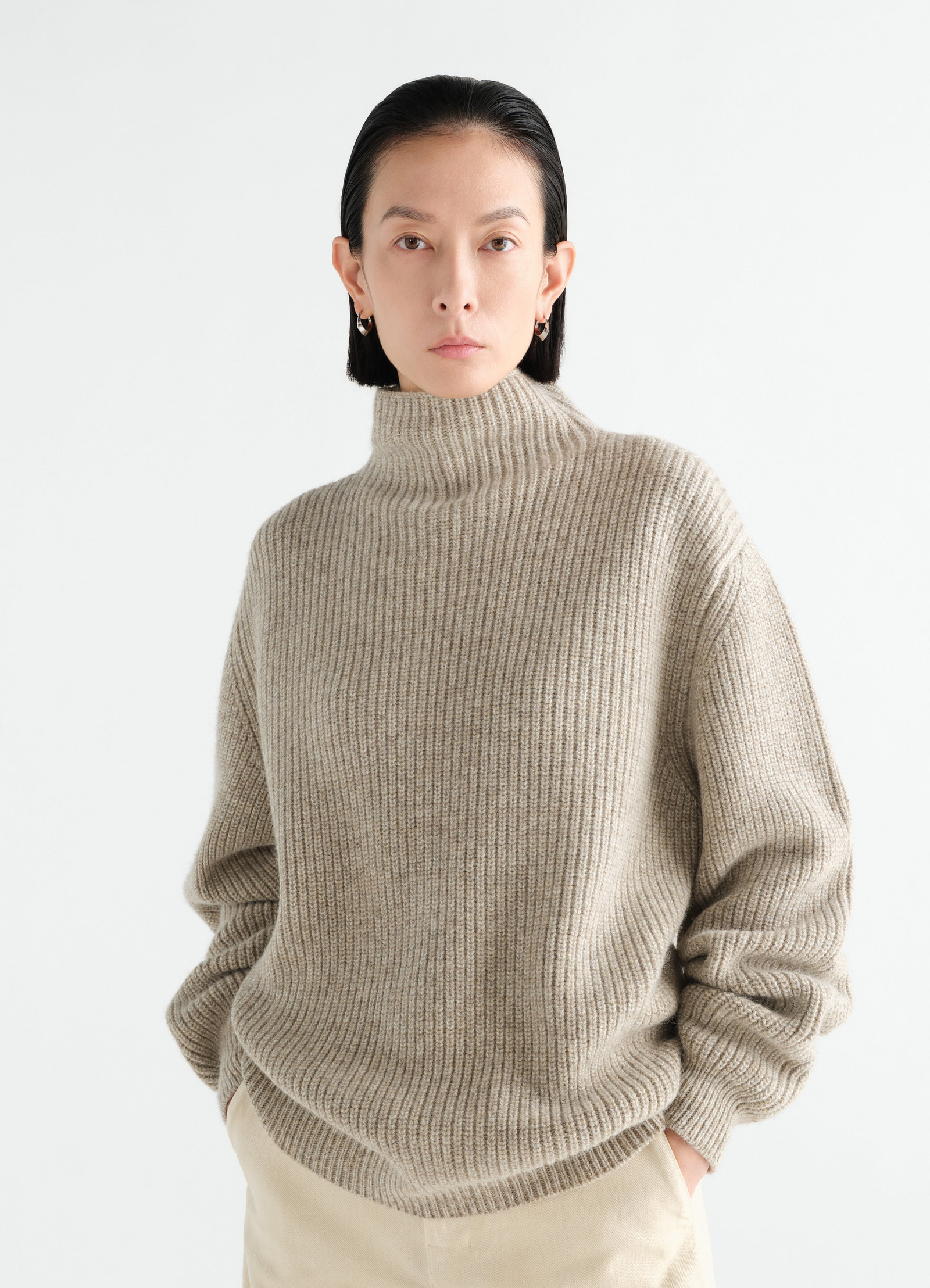 High neck beige yak alpaca sweater by lemaire worn by model front view with hands in pockets