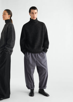 High neck black yak alpaca sweater by lemaire worn by male model front view with gray pants and black shoes