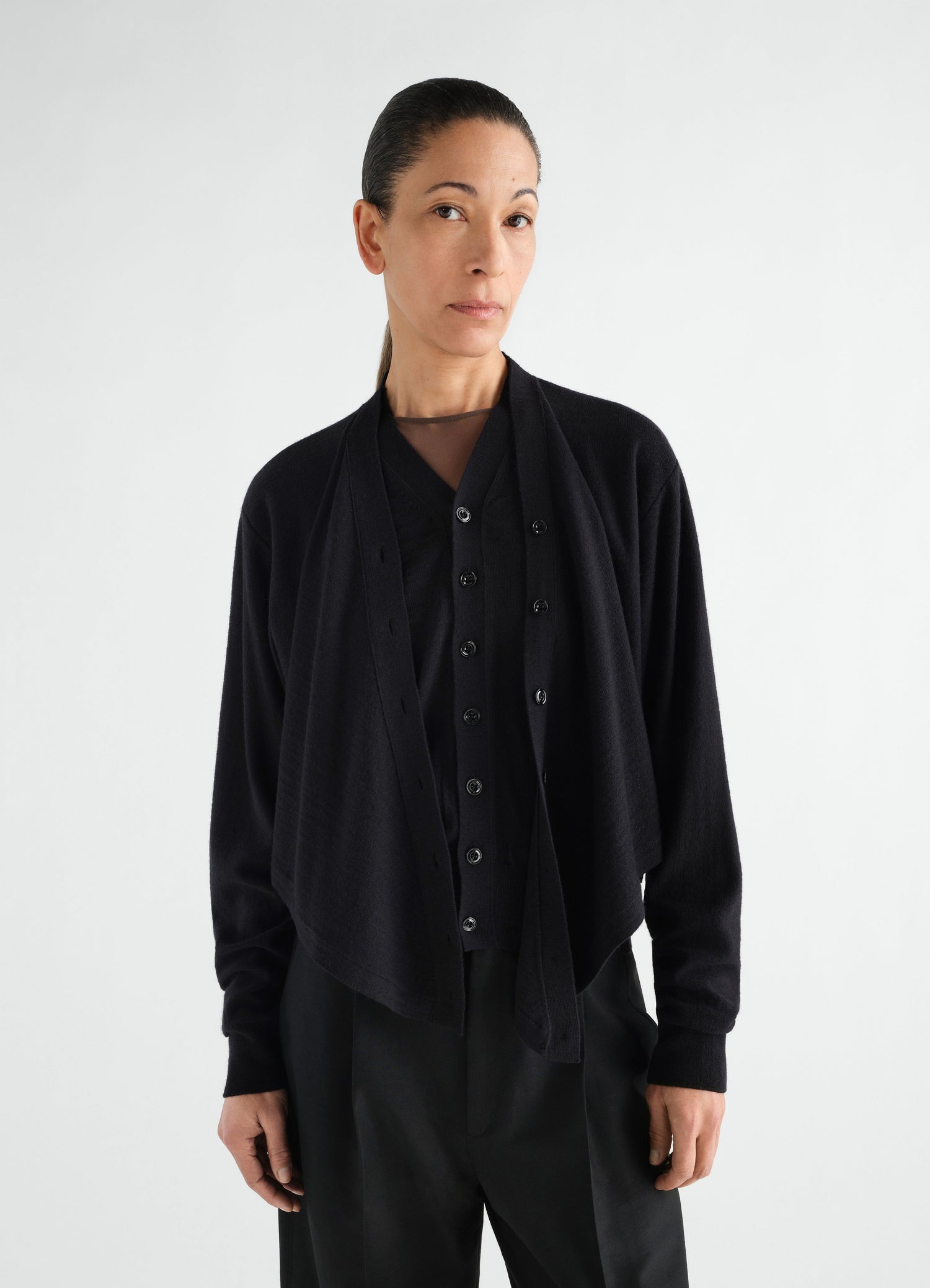 Trompe-L’Œil black merino wool blend cardigan by LEMAIRE worn by a model front view with button detail