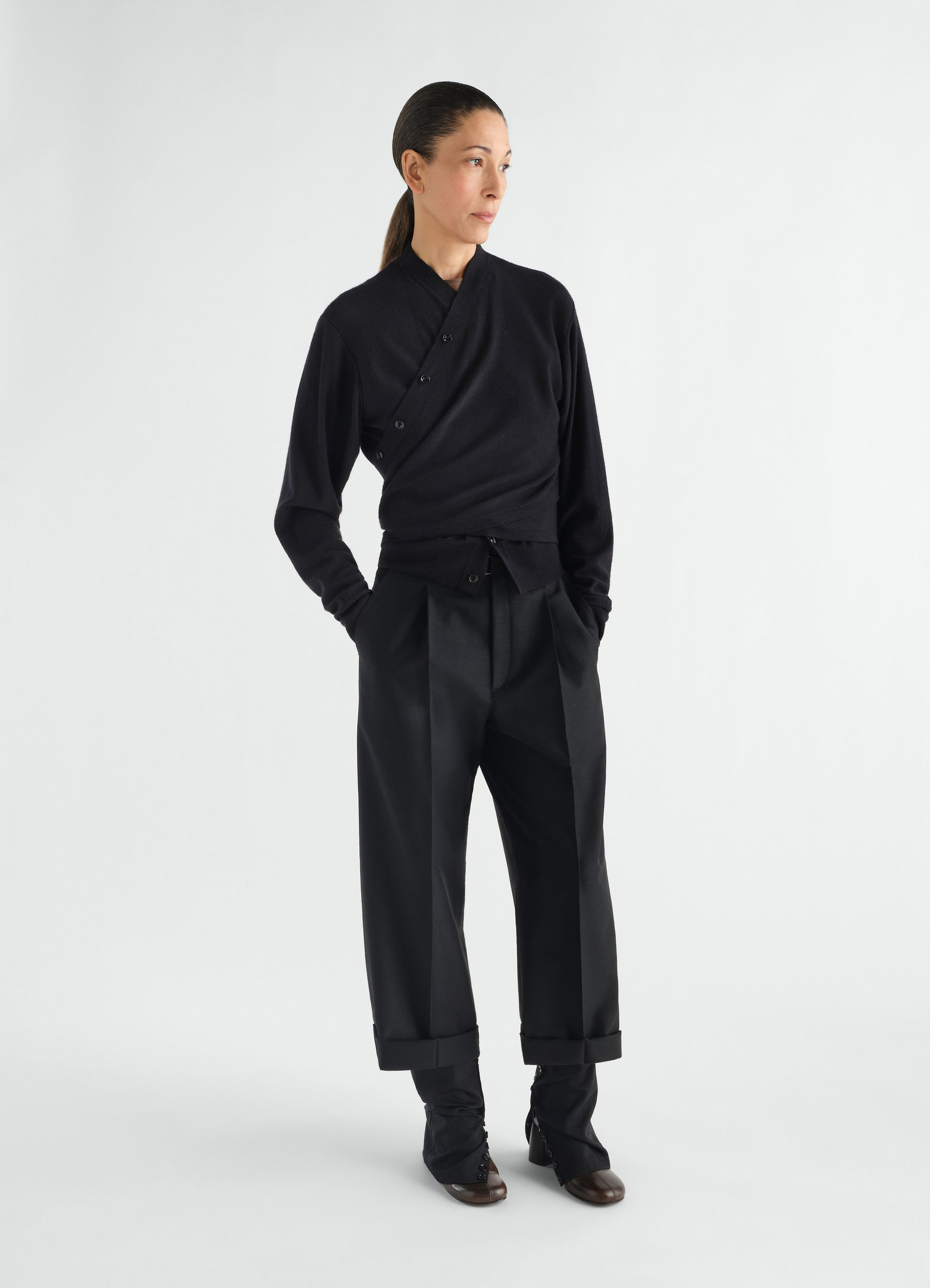 Black merino wool blend trompe-l’œil cardigan by lemaire worn by model with black tailored trousers front view