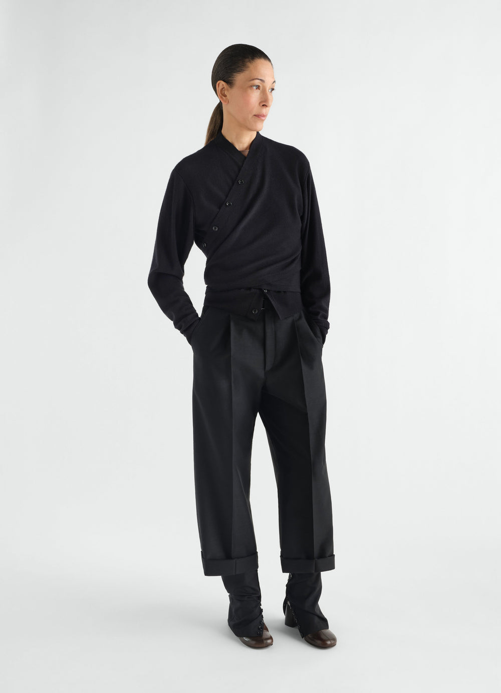 Black merino wool blend trompe-l’œil cardigan by LEMAIRE worn by model with black tailored trousers front view