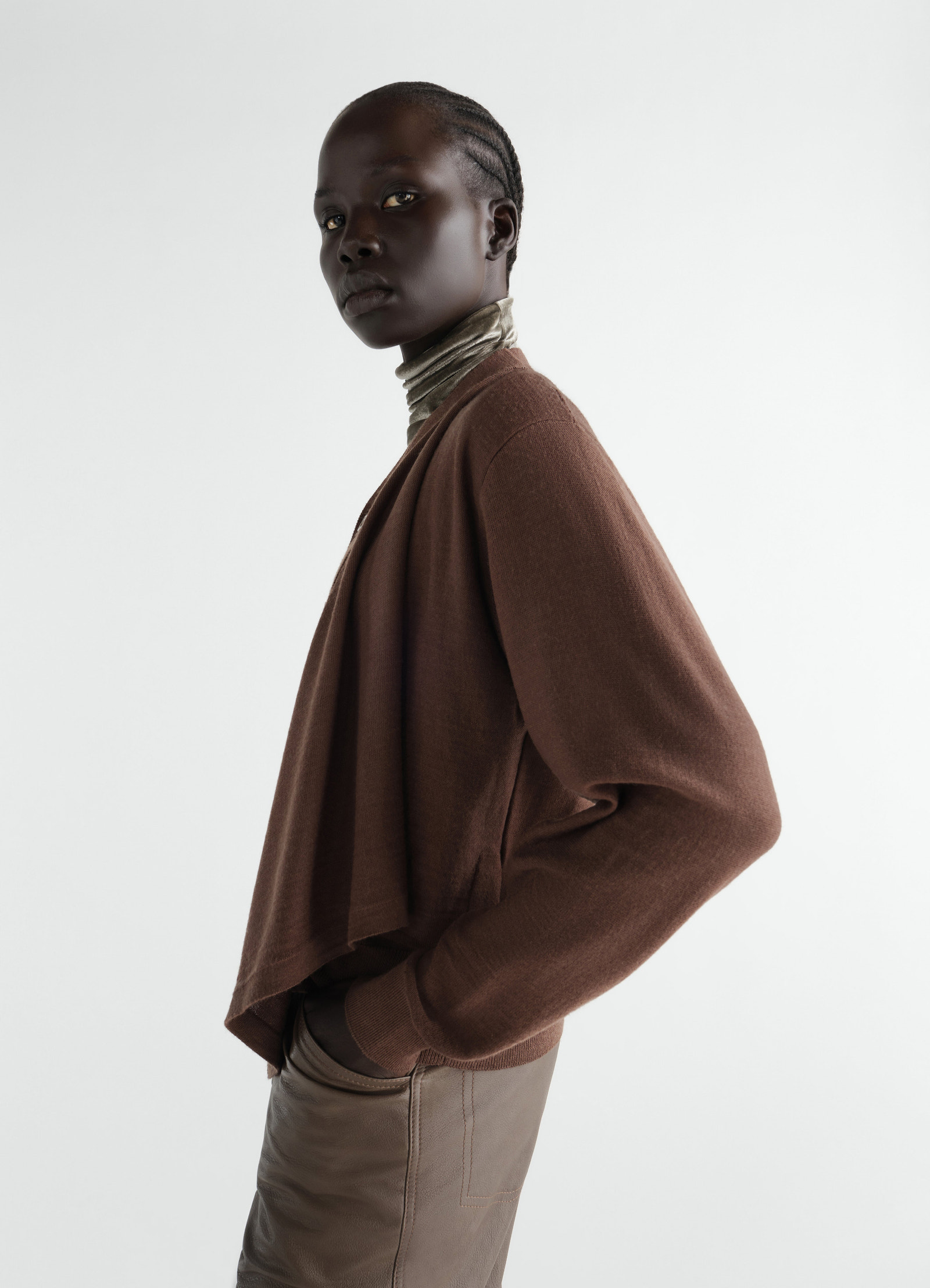 Trompe-l’œil brown merino wool blend cardigan by lemaire worn by model side view with taupe leather pants and turtleneck