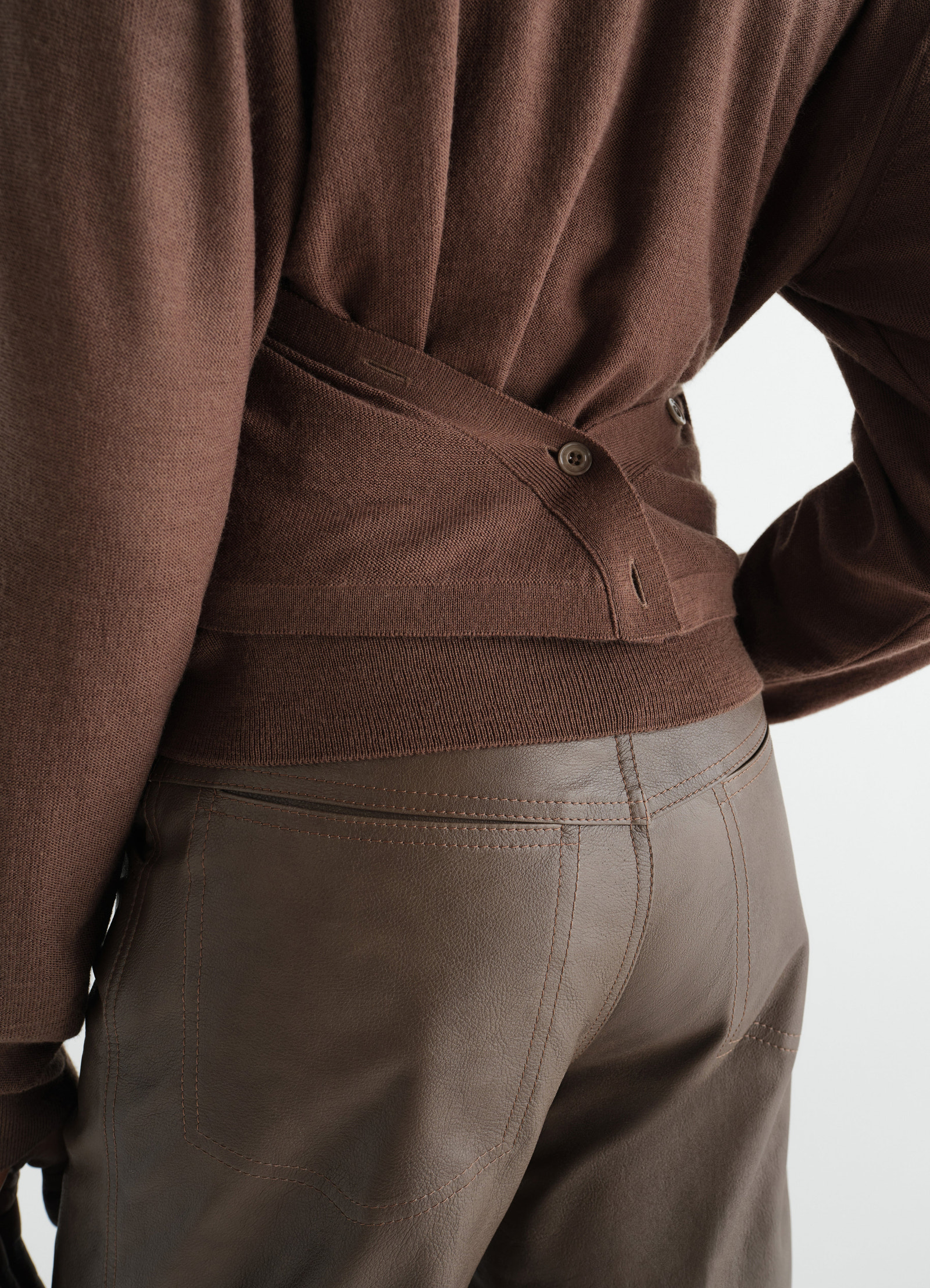 Brown merino wool blend cardigan with button detail and brown leather pants worn by model lemaire close-up back view