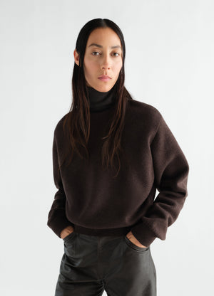 Short dark brown felted merino wool turtleneck sweater by lemaire worn by a model front view