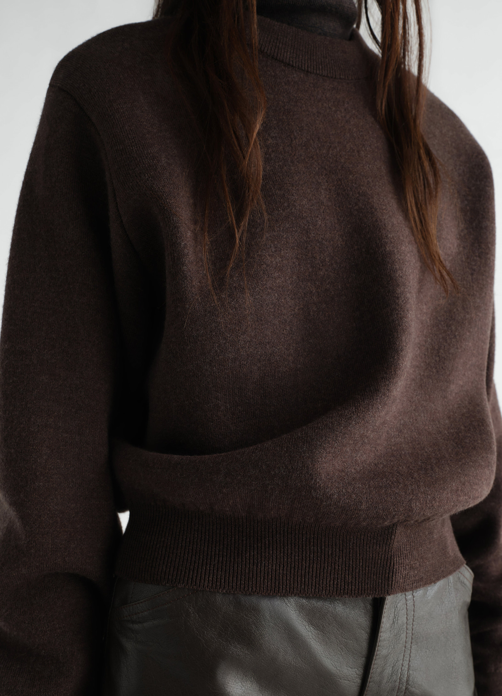 Short brown felted merino wool sweater by lemaire worn by a model with turtleneck and ribbed hem close-up