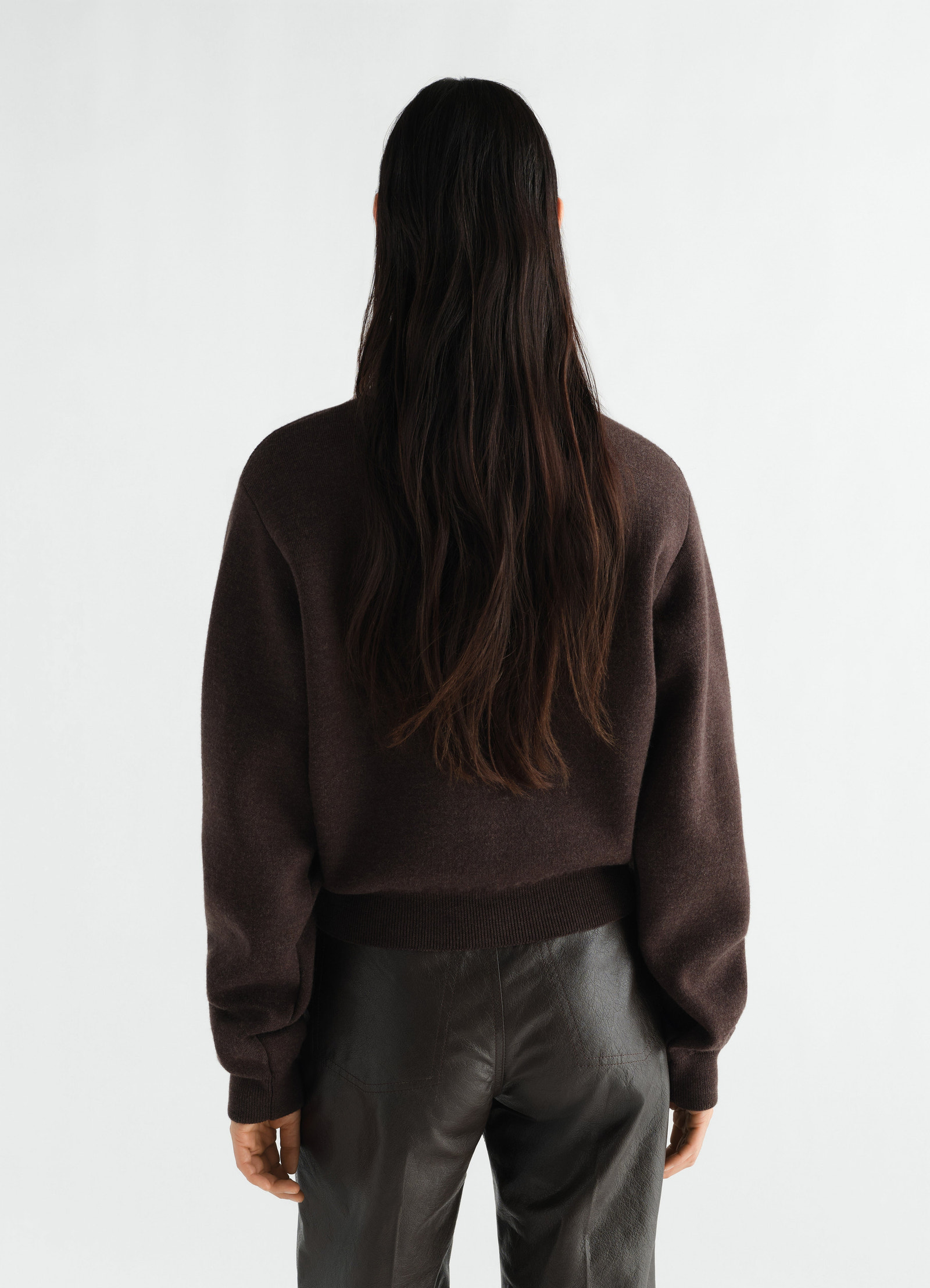 Short dark brown merino wool sweater by lemaire worn by model back view with leather pants