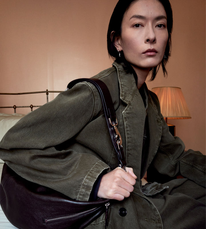 Olive green trench coat in olive green cotton, model shot, worn view, side angle relaxed fit