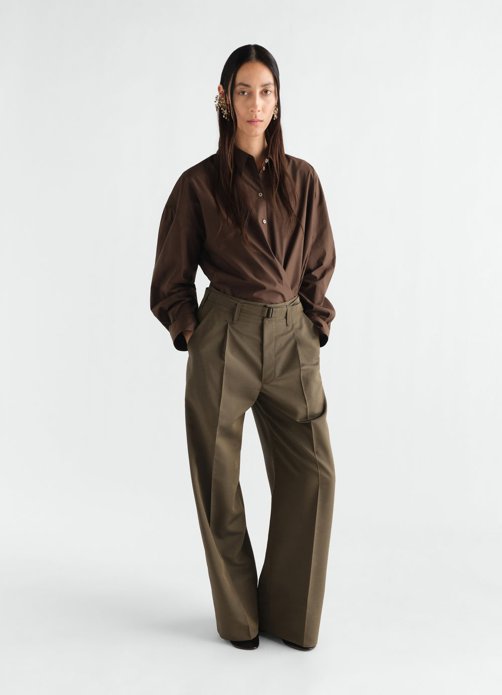 Straight collar twisted brown cotton shirt by LEMAIRE worn by model front view with hands in pockets