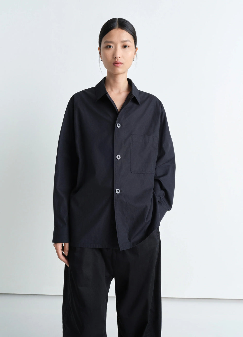 Lemaire Pyjama Shirt in Black Heavy Cotton Washed Poplin, model shot, three-quarter view relaxed fit with cuffed sleeves