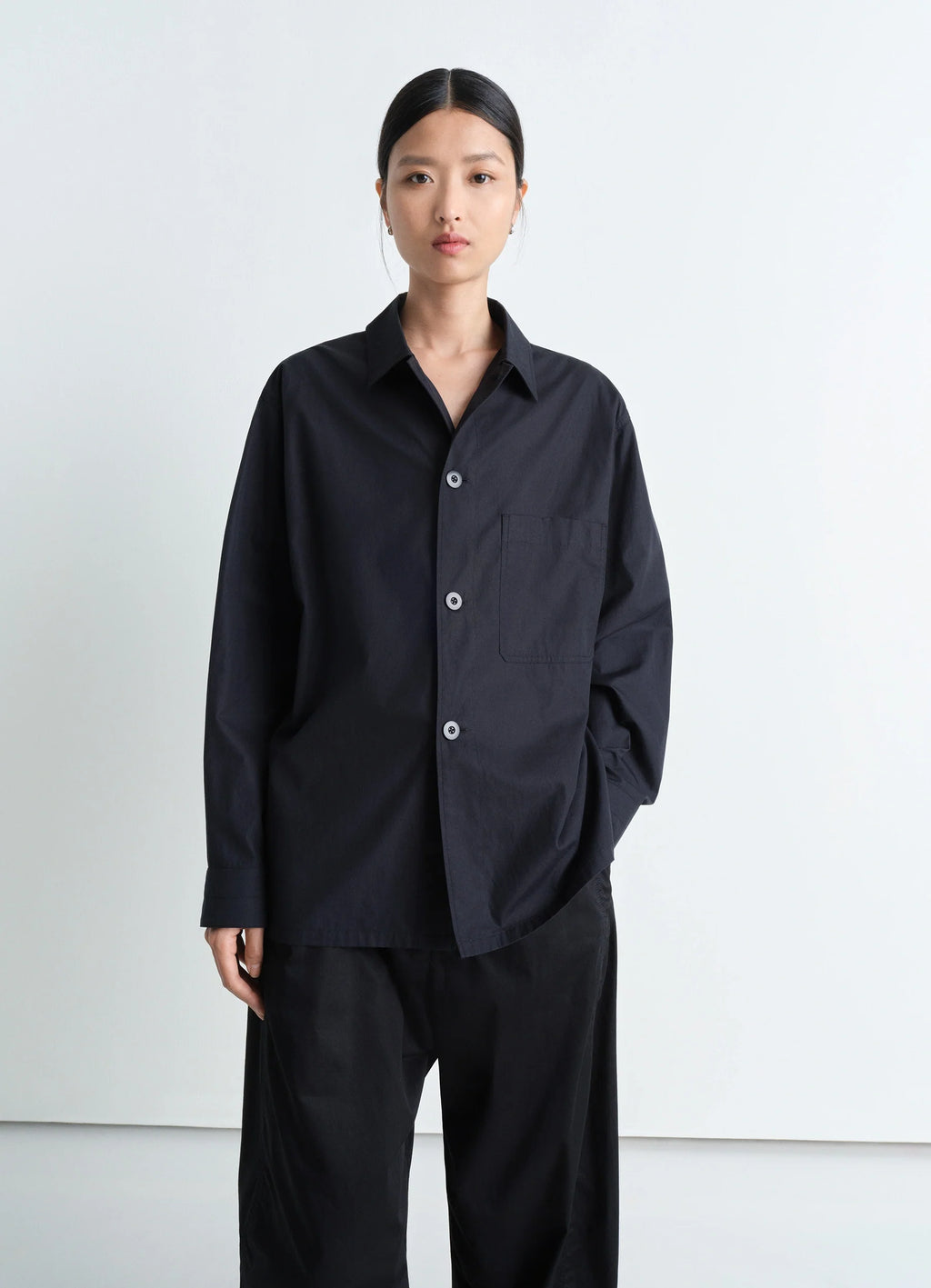 Lemaire Pyjama Shirt in Black Heavy Cotton Washed Poplin, model shot, three-quarter view relaxed fit with cuffed sleeves